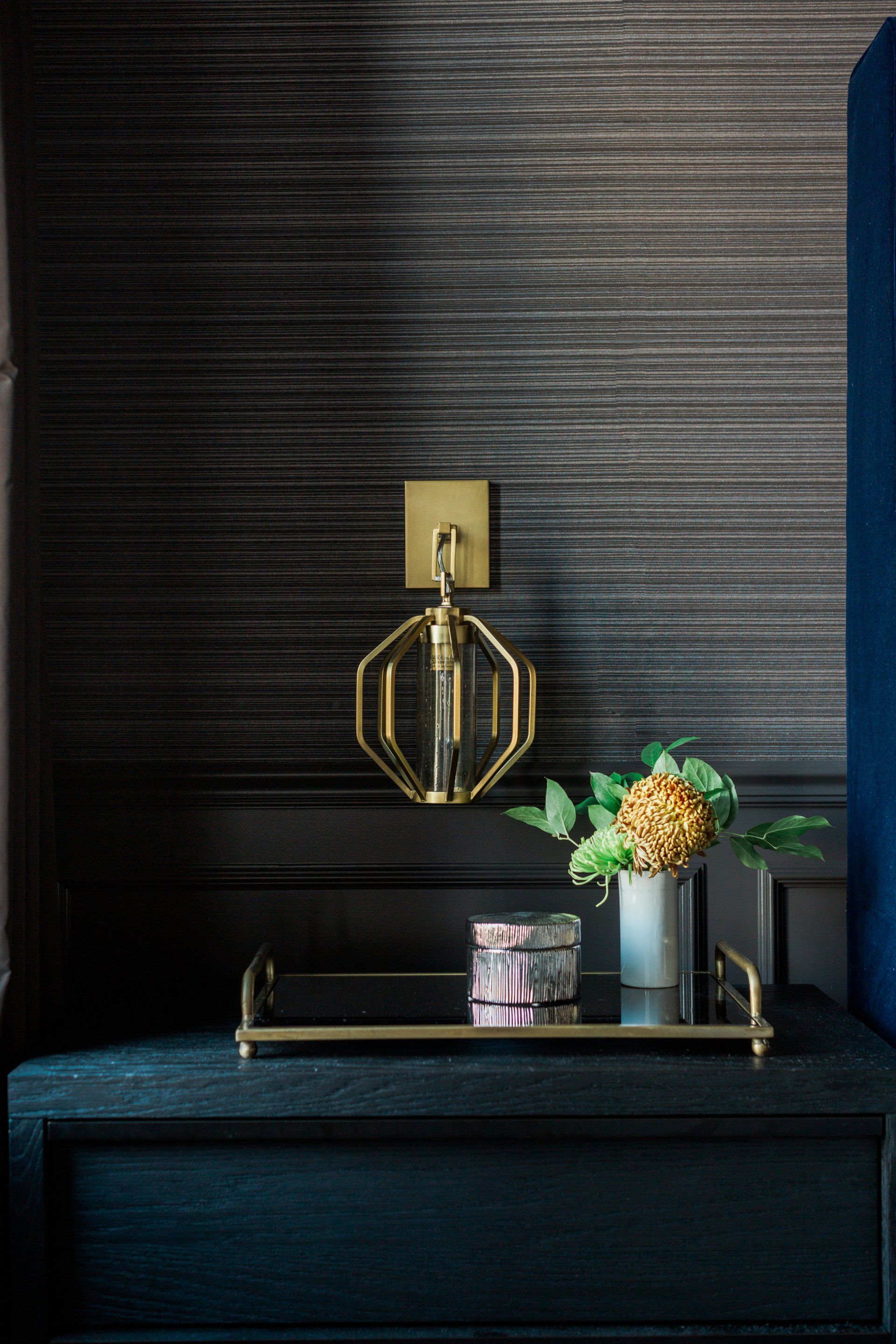 A nightstand with a vase of flowers and a lamp on it.