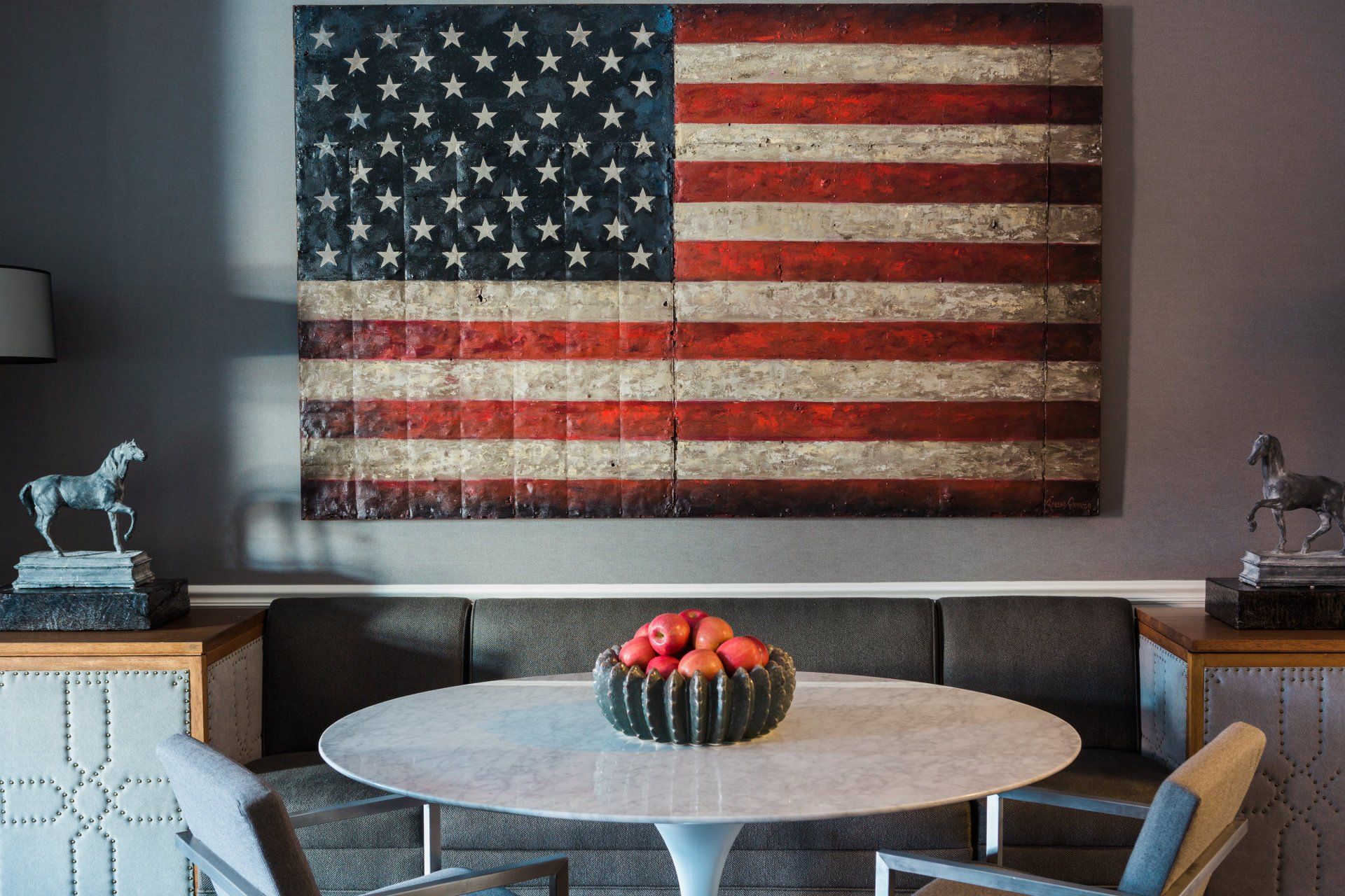 A large american flag is hanging on a wall above a dining table