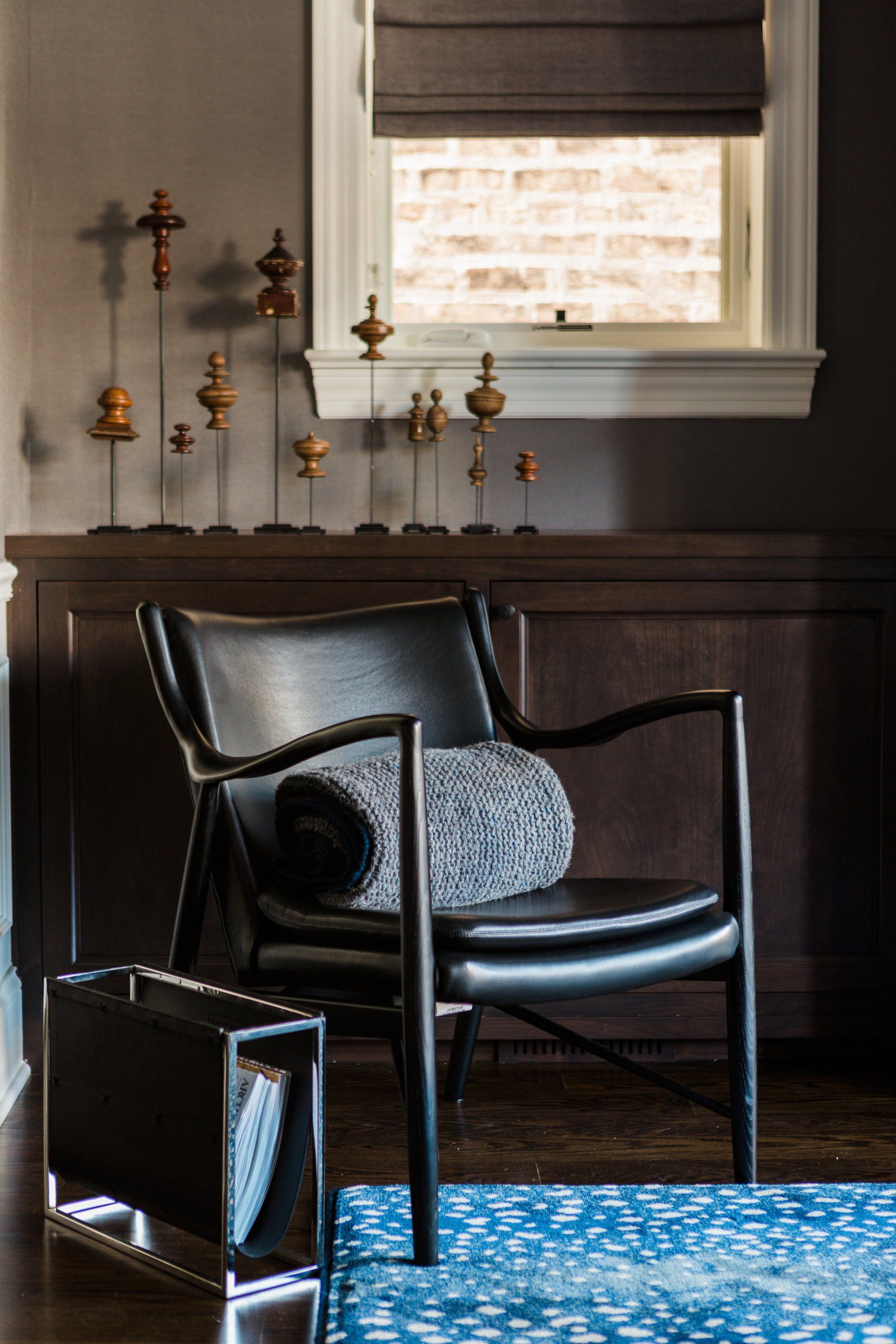 A black chair is sitting in a living room next to a window.