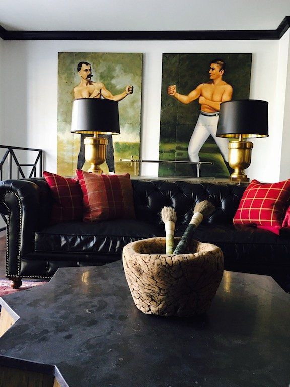 A living room with a black couch and two paintings on the wall