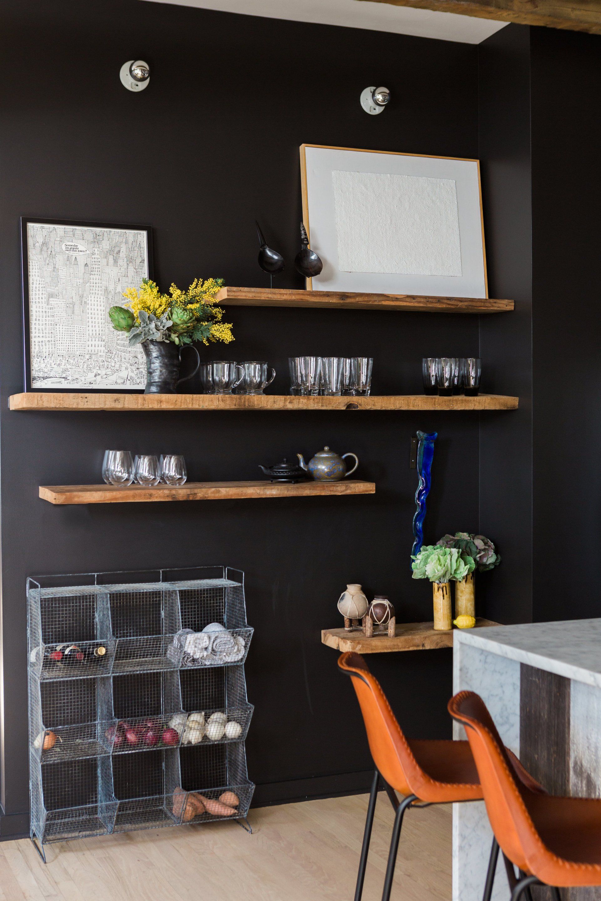 A kitchen with black walls and wooden shelves.
