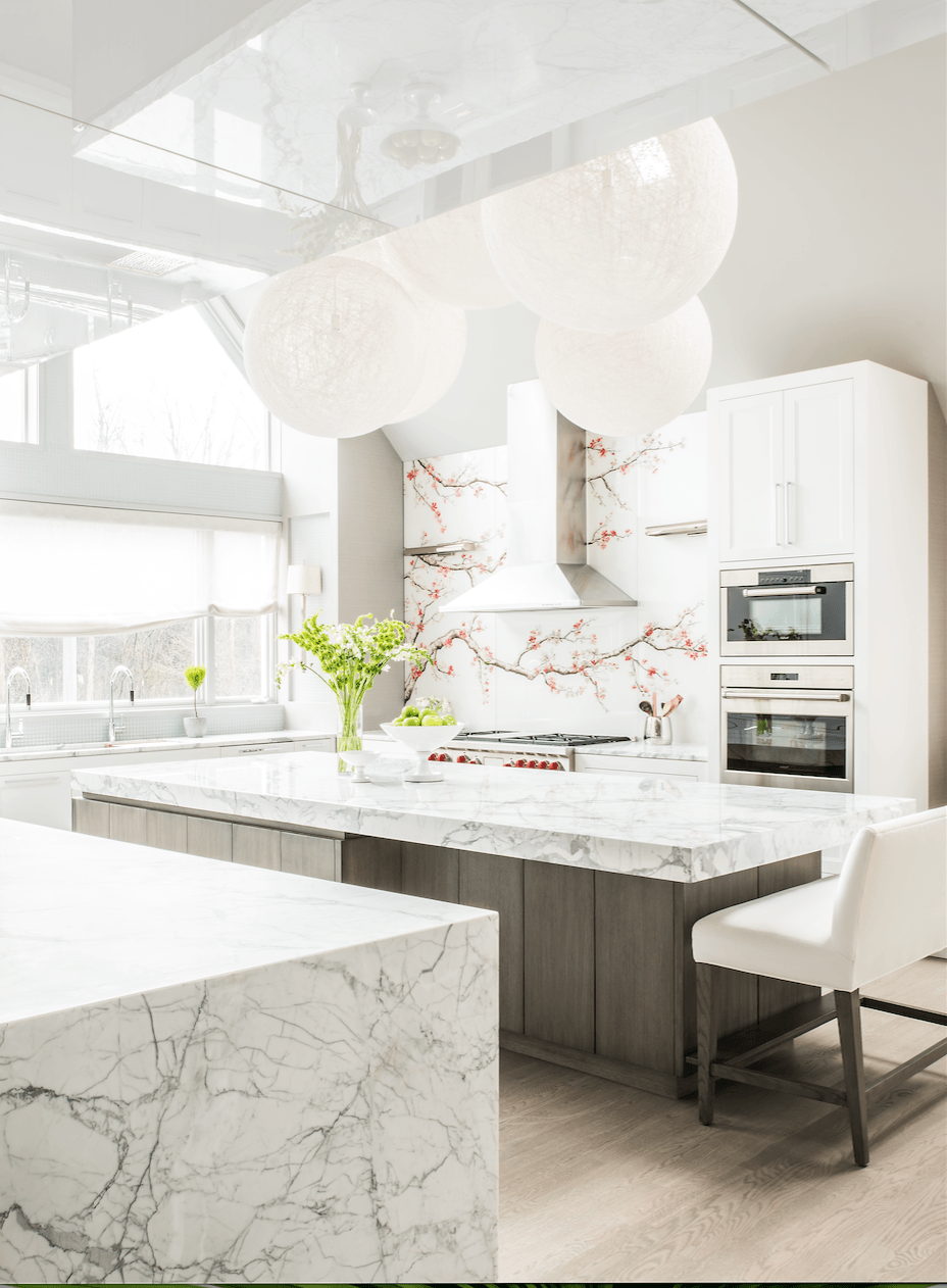 A kitchen with white cabinets and marble counter tops