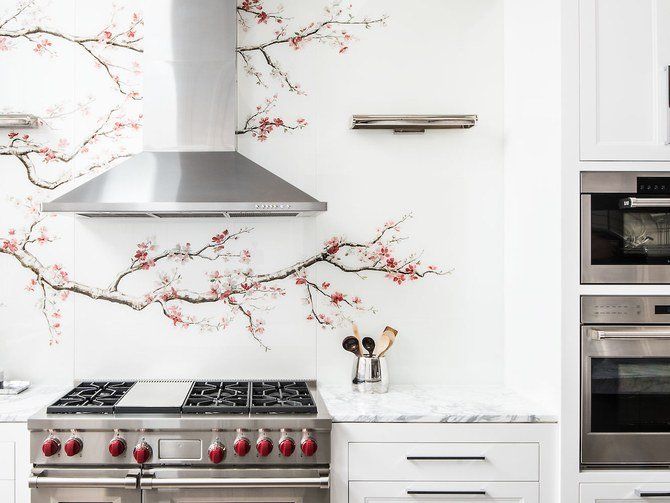 A kitchen with a stove , oven , microwave and a cherry blossom wall mural.