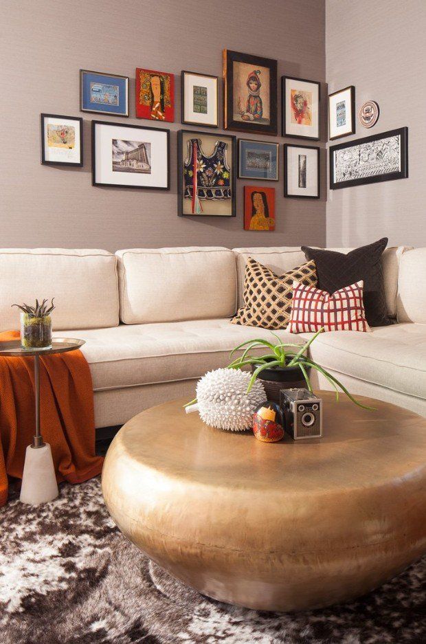 A living room with a couch , coffee table , and pictures on the wall.
