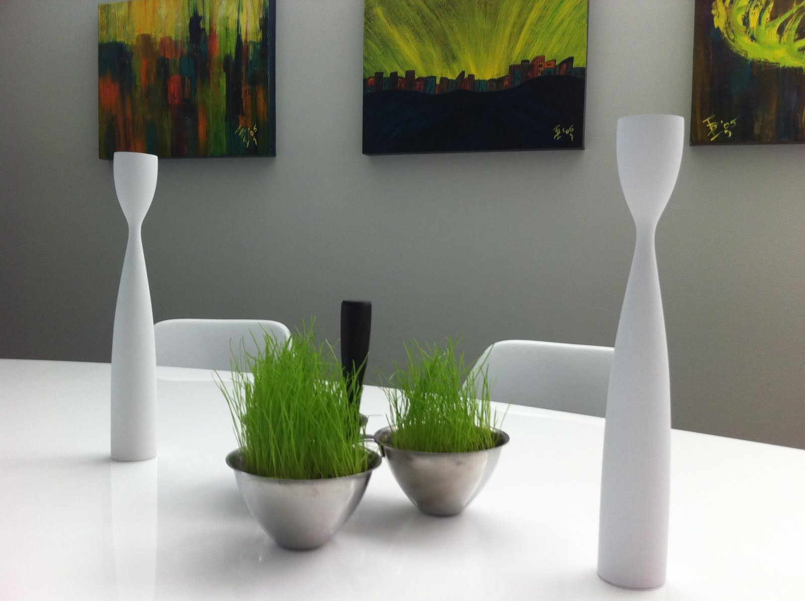 Two bowls of grass sit on a white table