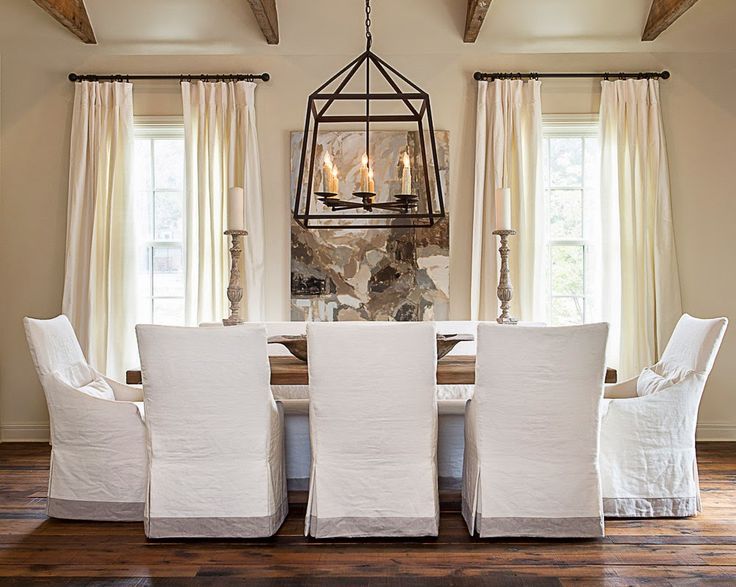 A dining room with white chairs and a chandelier