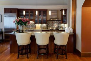 A kitchen with three chairs and a vase of flowers on the counter.