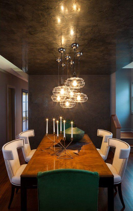 A dining room with a long table and chairs and a chandelier hanging from the ceiling.