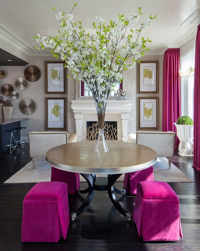 A living room with a round table and pink ottomans
