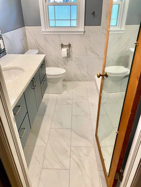 A bathroom with a toilet , sink and mirror.