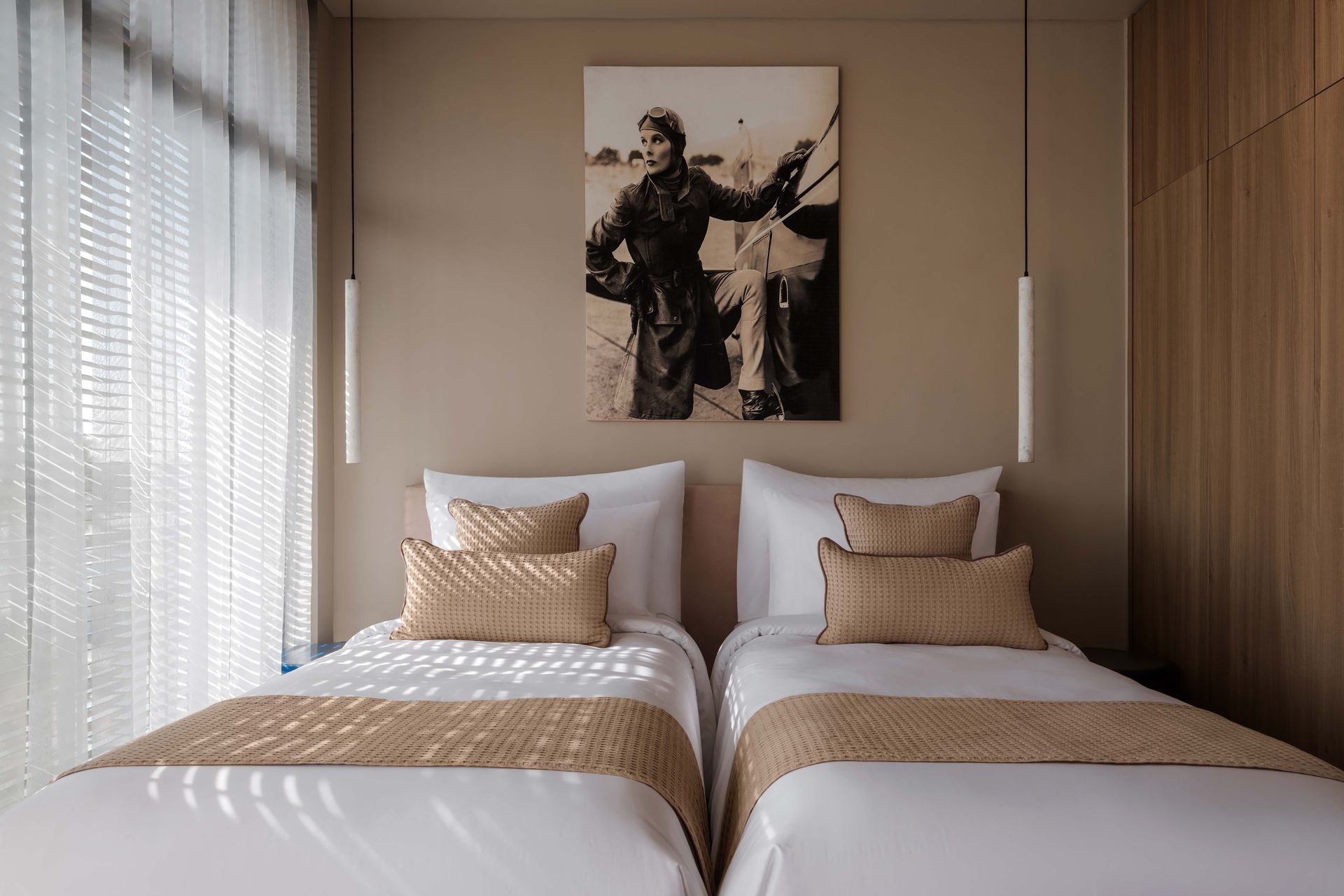 A hotel room with two beds and a painting on the wall.