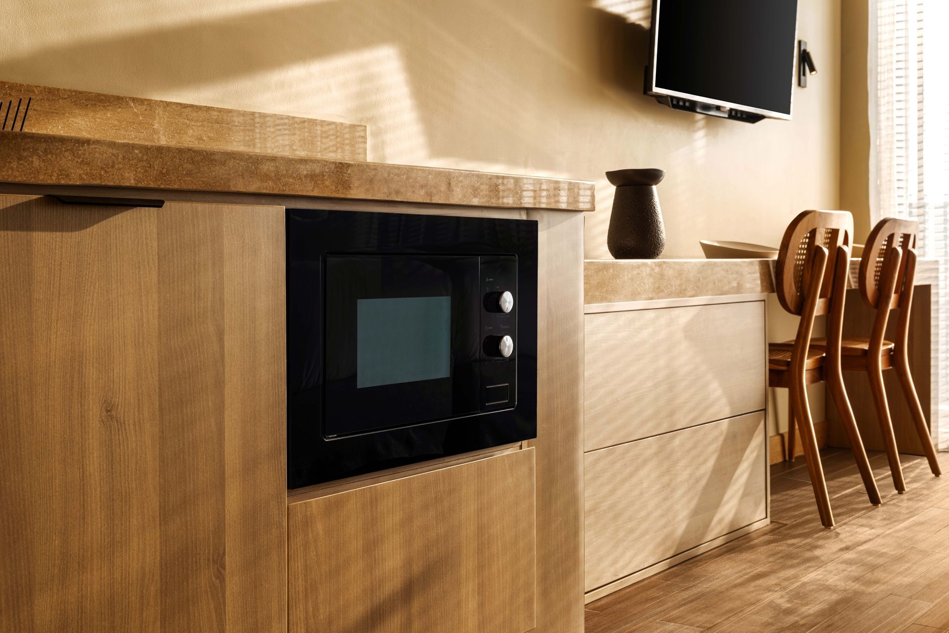 A kitchen with a microwave and a television on the wall.