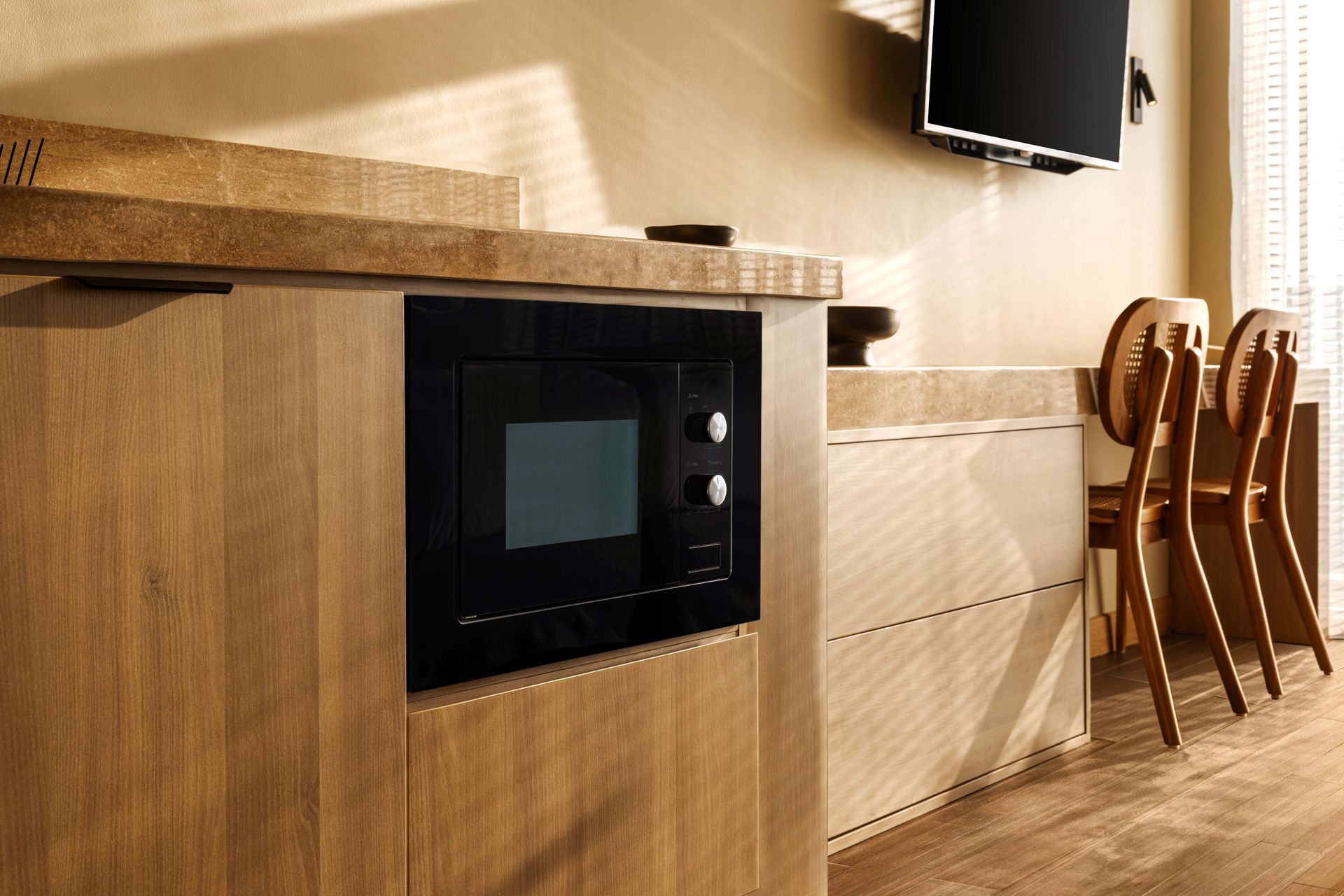 A kitchen with a microwave and a television on the wall.