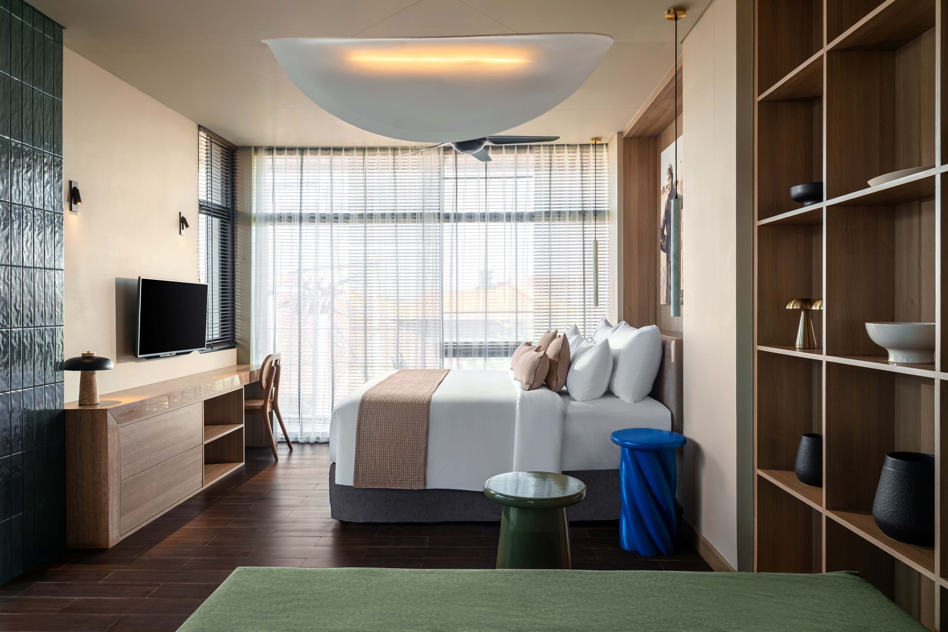 A hotel room with a large bed , television , and shelves.