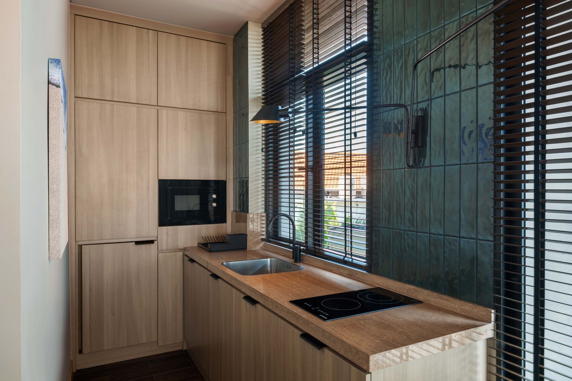 A kitchen with wooden cabinets , a sink , a microwave and a window.