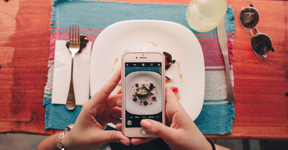 A person is taking a picture of a plate of food with a cell phone.