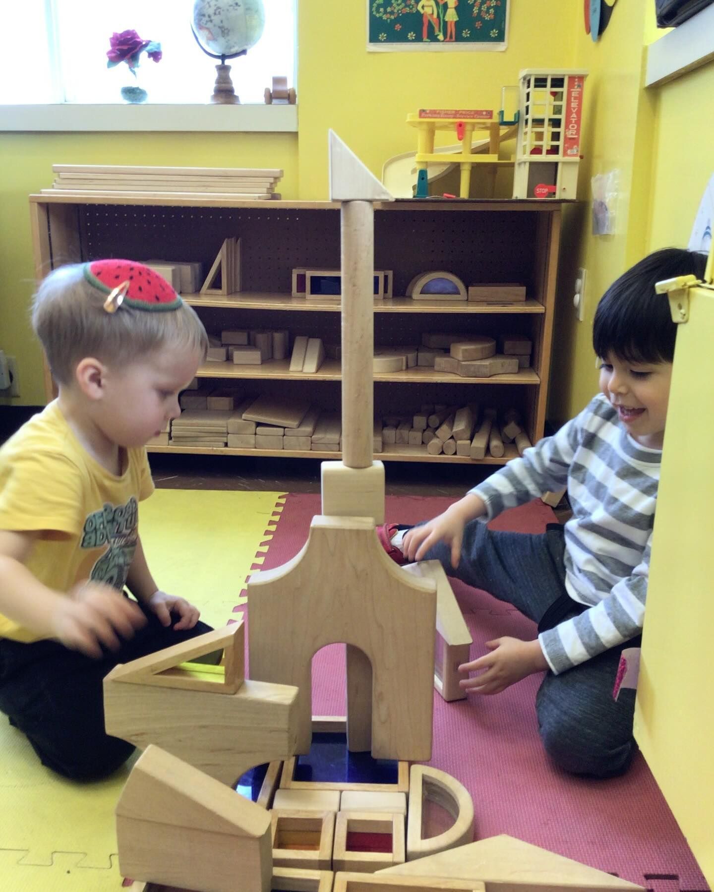 Two children are playing with wooden blocks on the floor