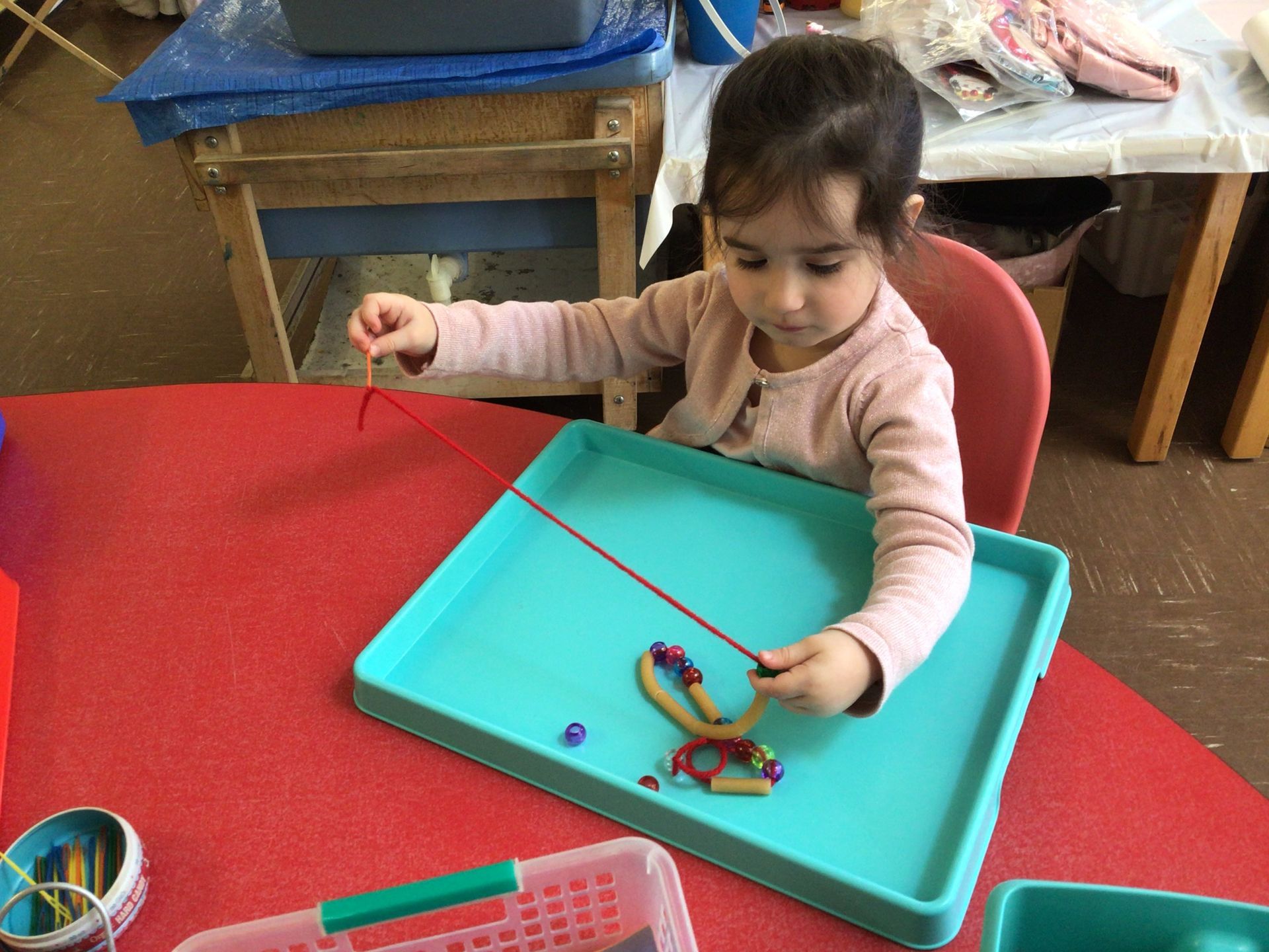 A little girl is sitting at a table playing with a toy.