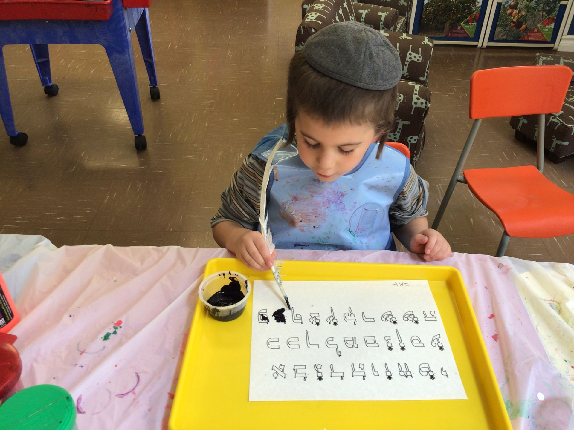 A young boy is writing on a piece of paper with a brush