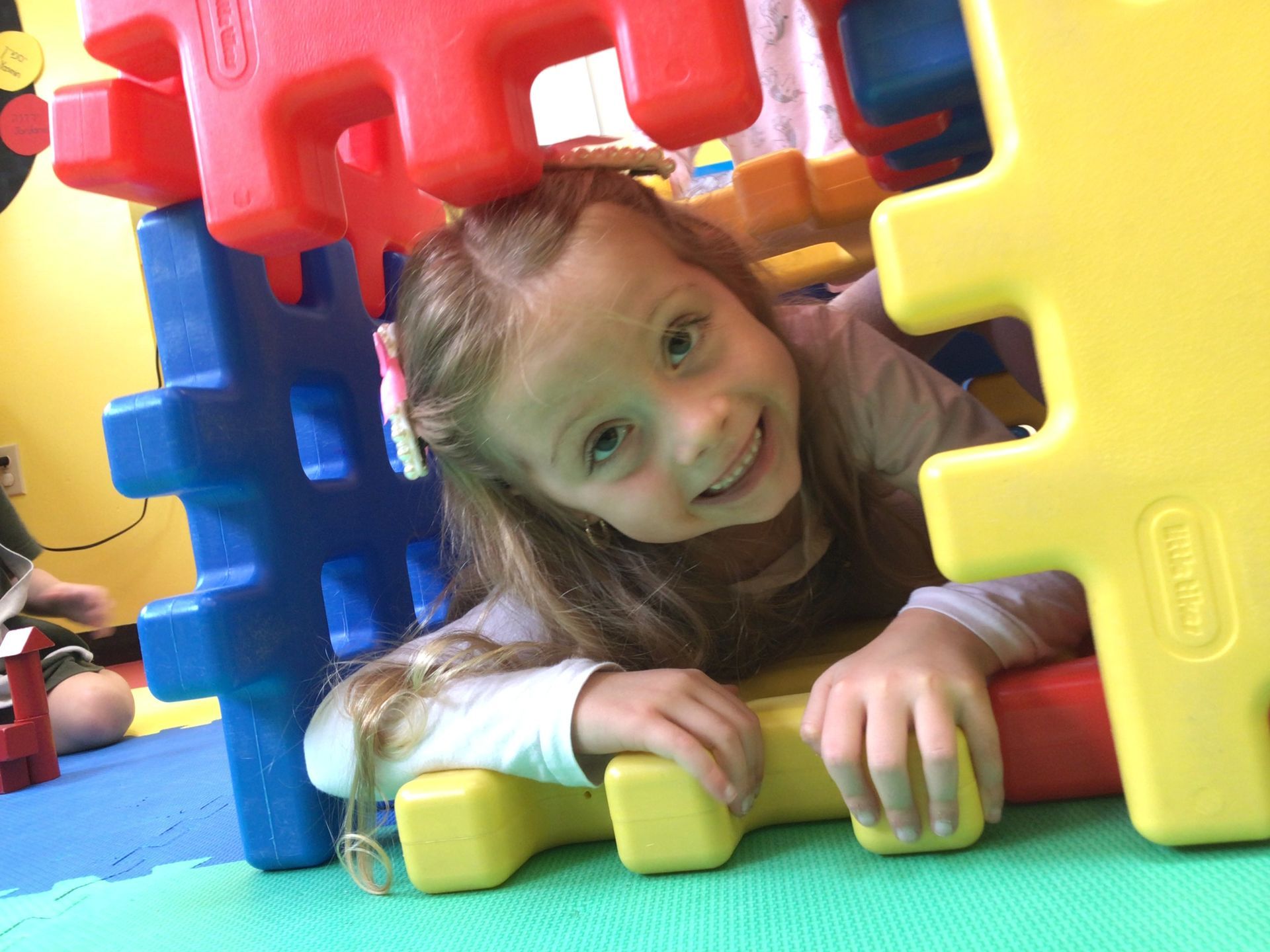 A little girl is laying on the floor playing with toys