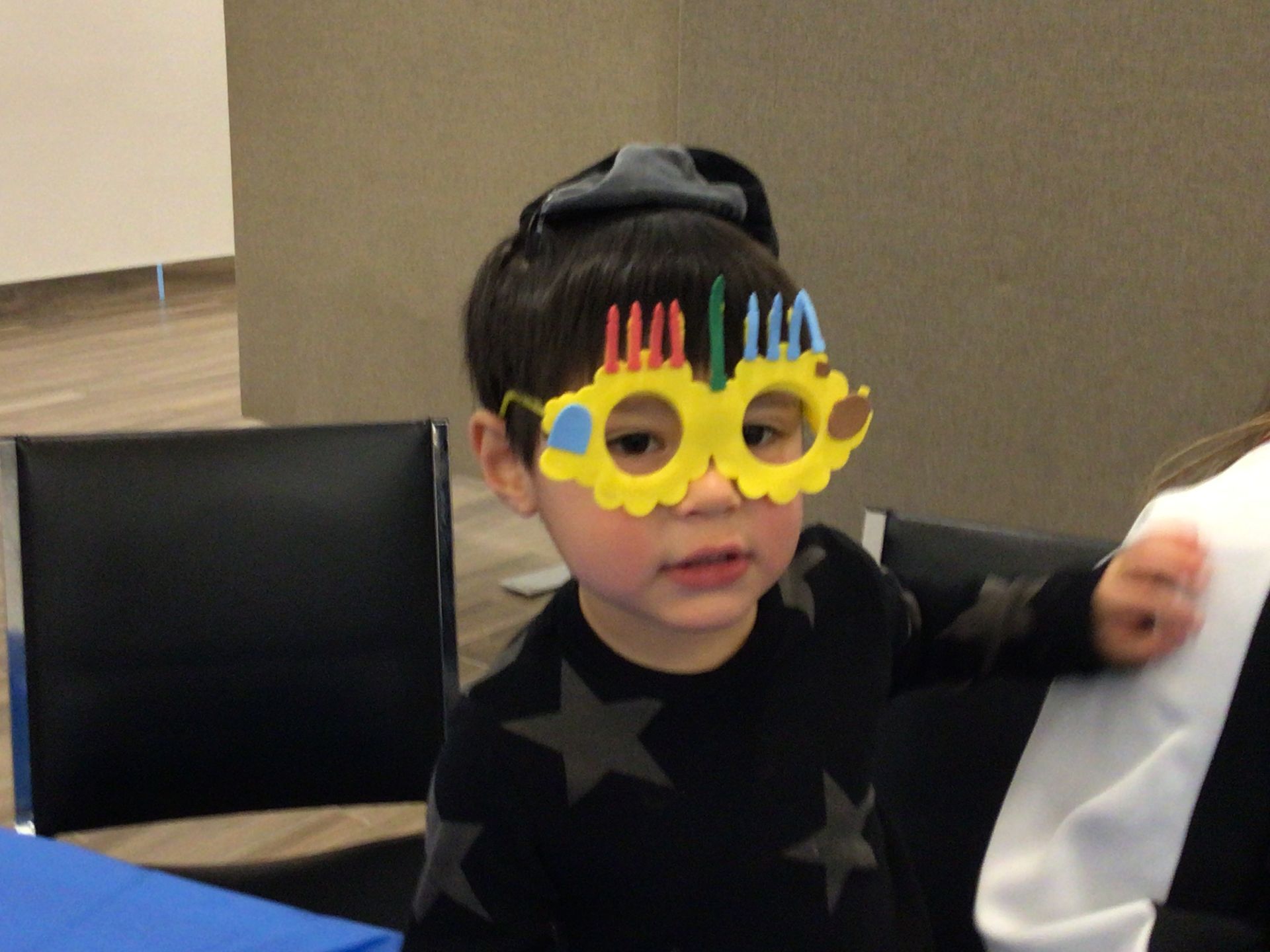 A young boy wearing a pair of glasses with candles on them