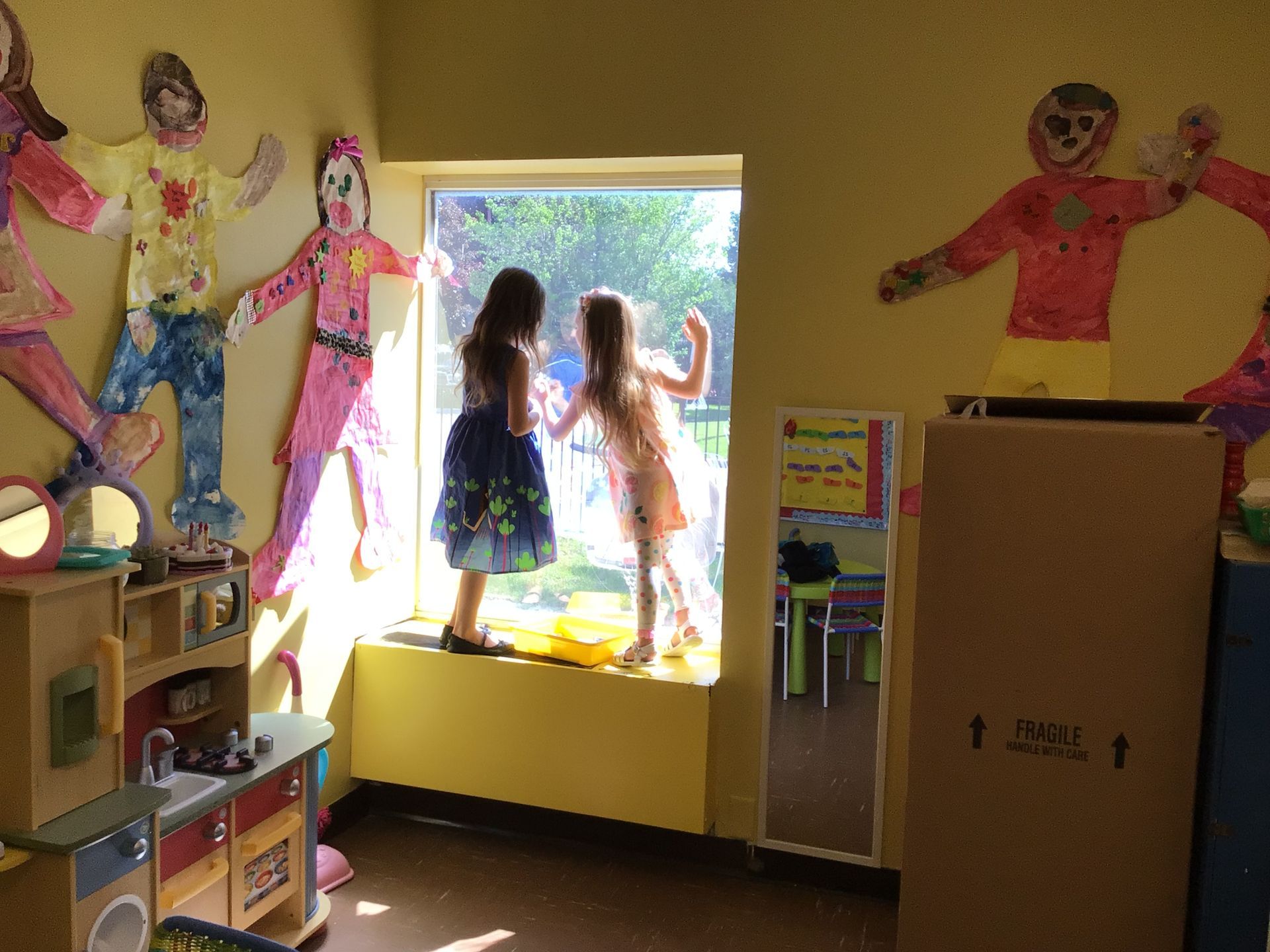 Two little girls are looking out of a window in a room
