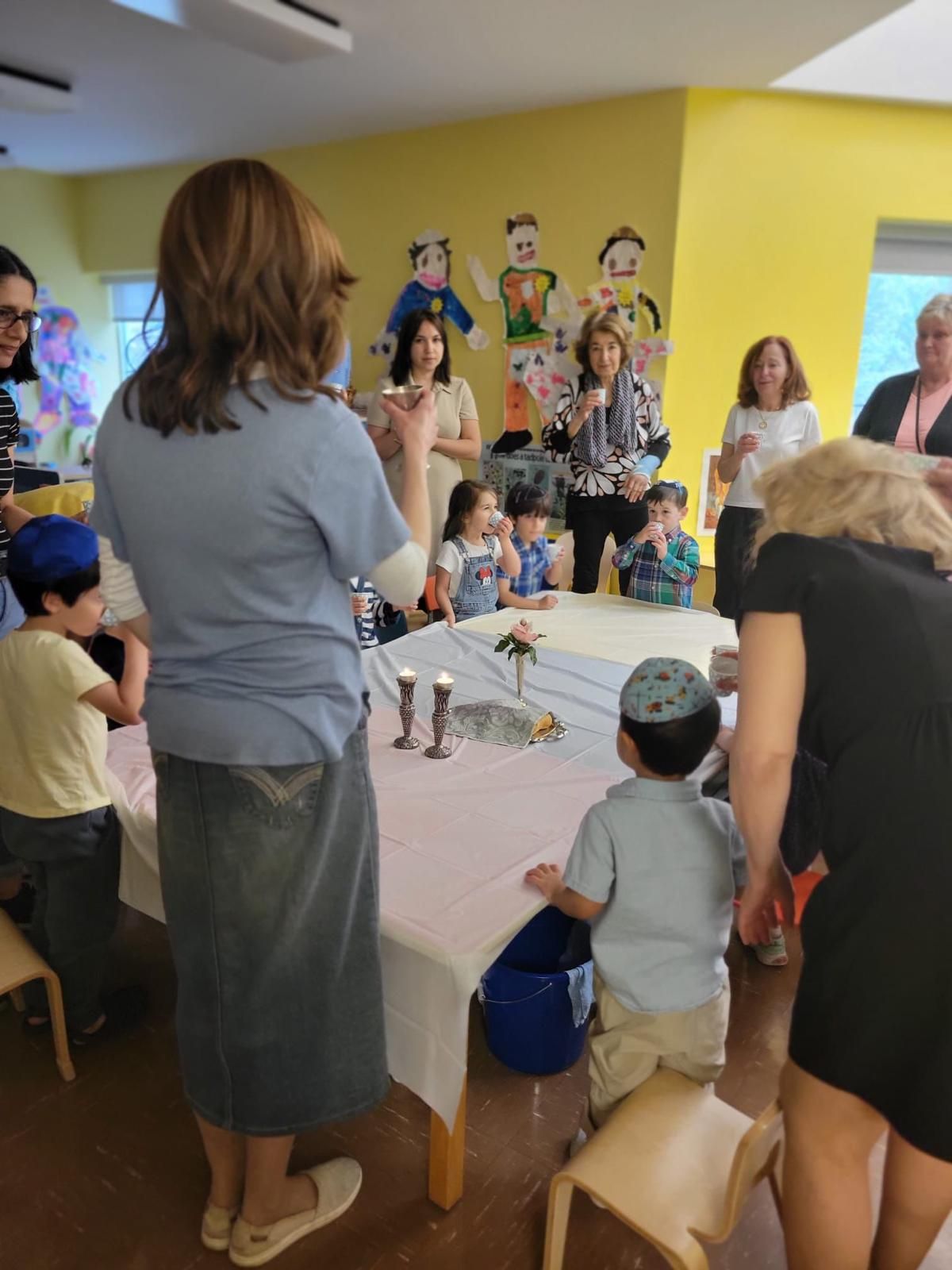 A group of people standing around a table during Shabbat