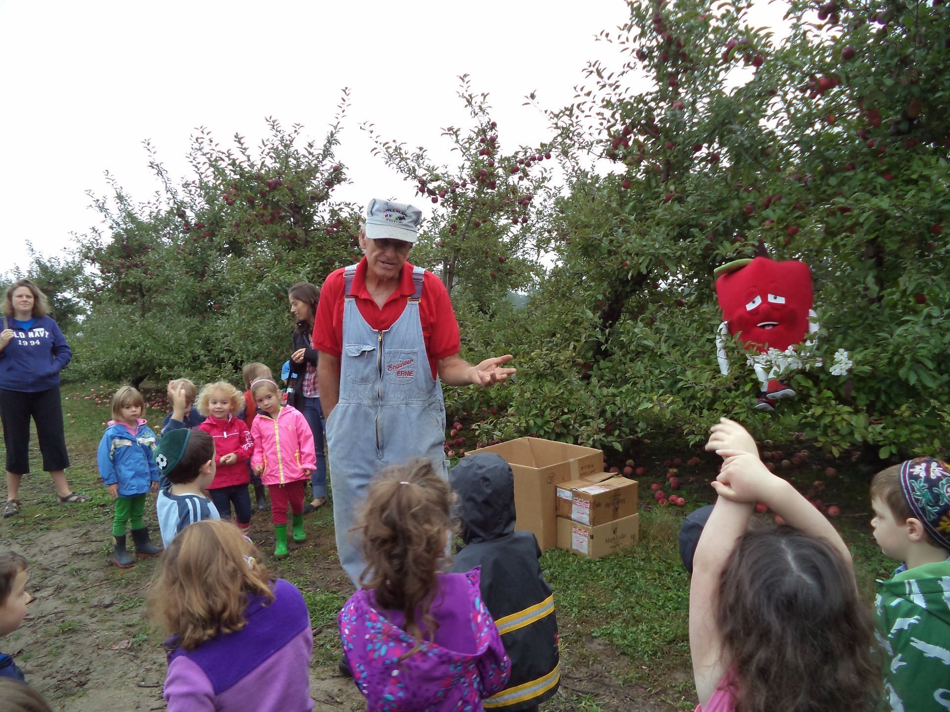 A man in overalls is talking to a group of children