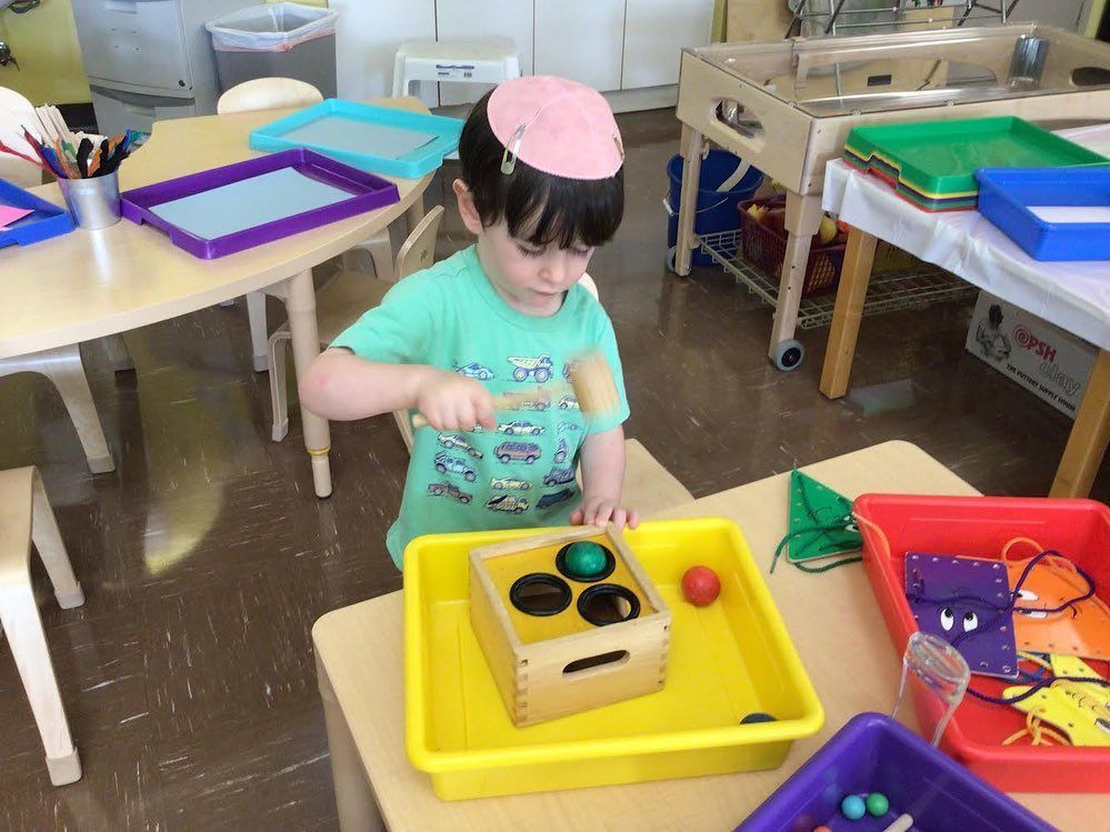 A little girl is sitting at a table playing with toys.
