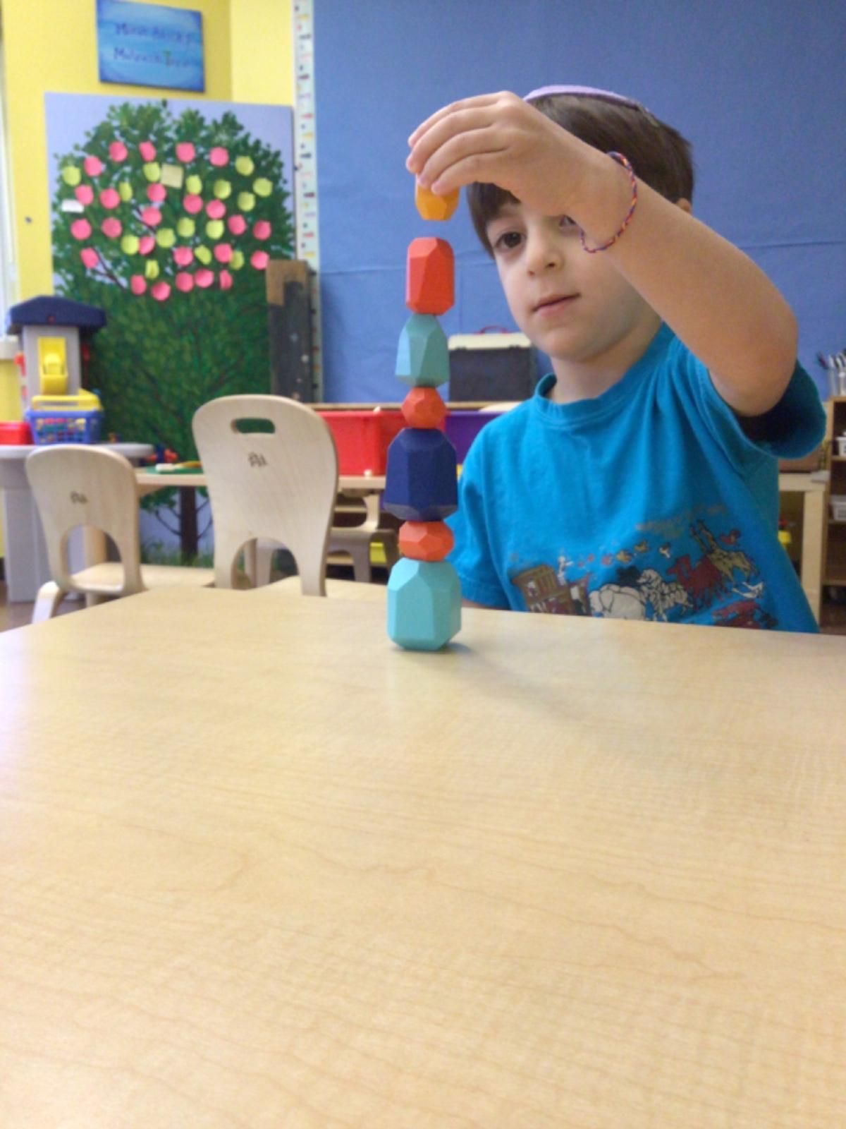 A boy in a blue shirt is stacking blocks on top of each other
