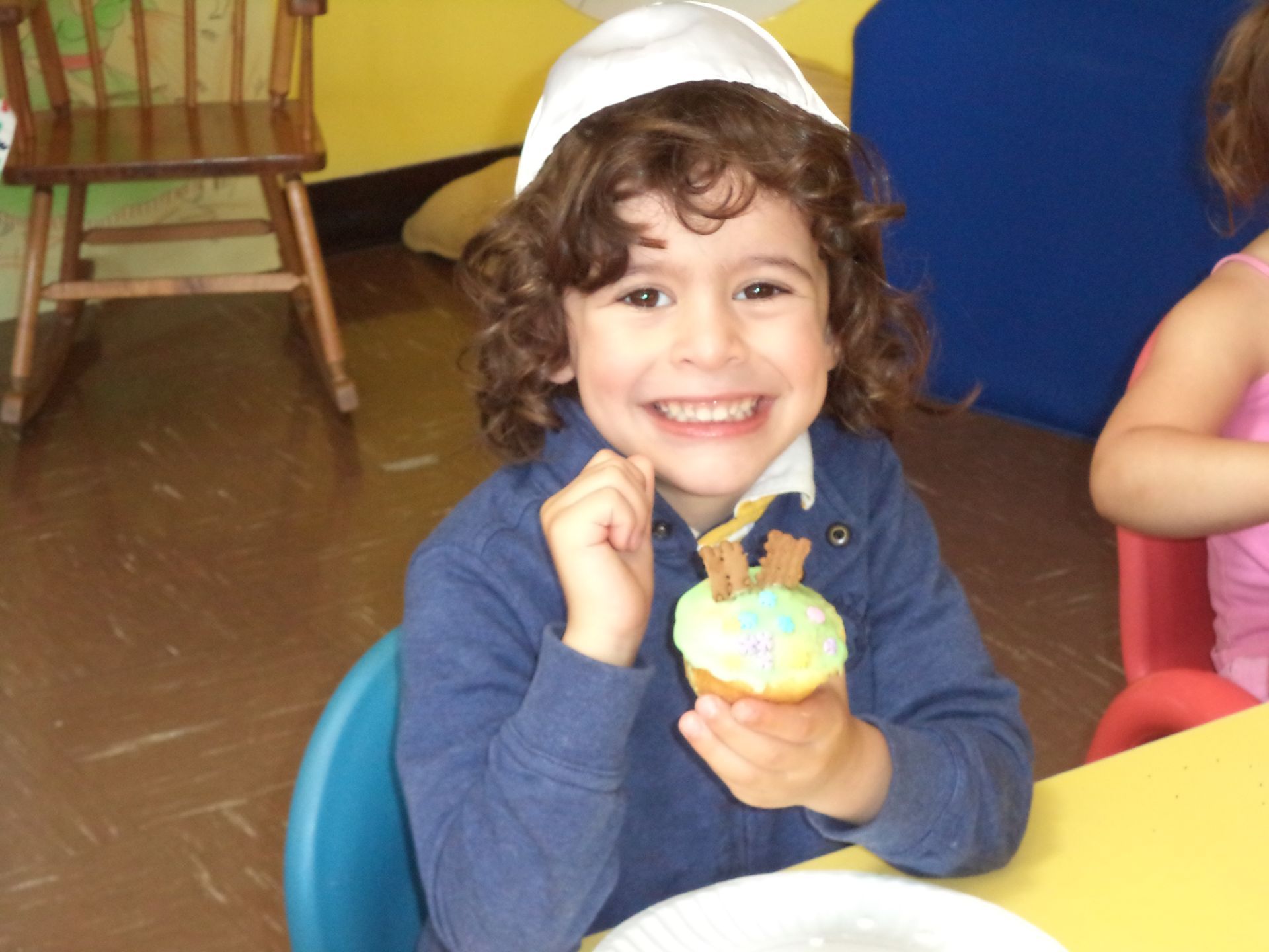 A young boy is holding a cupcake with a teddy bear on it