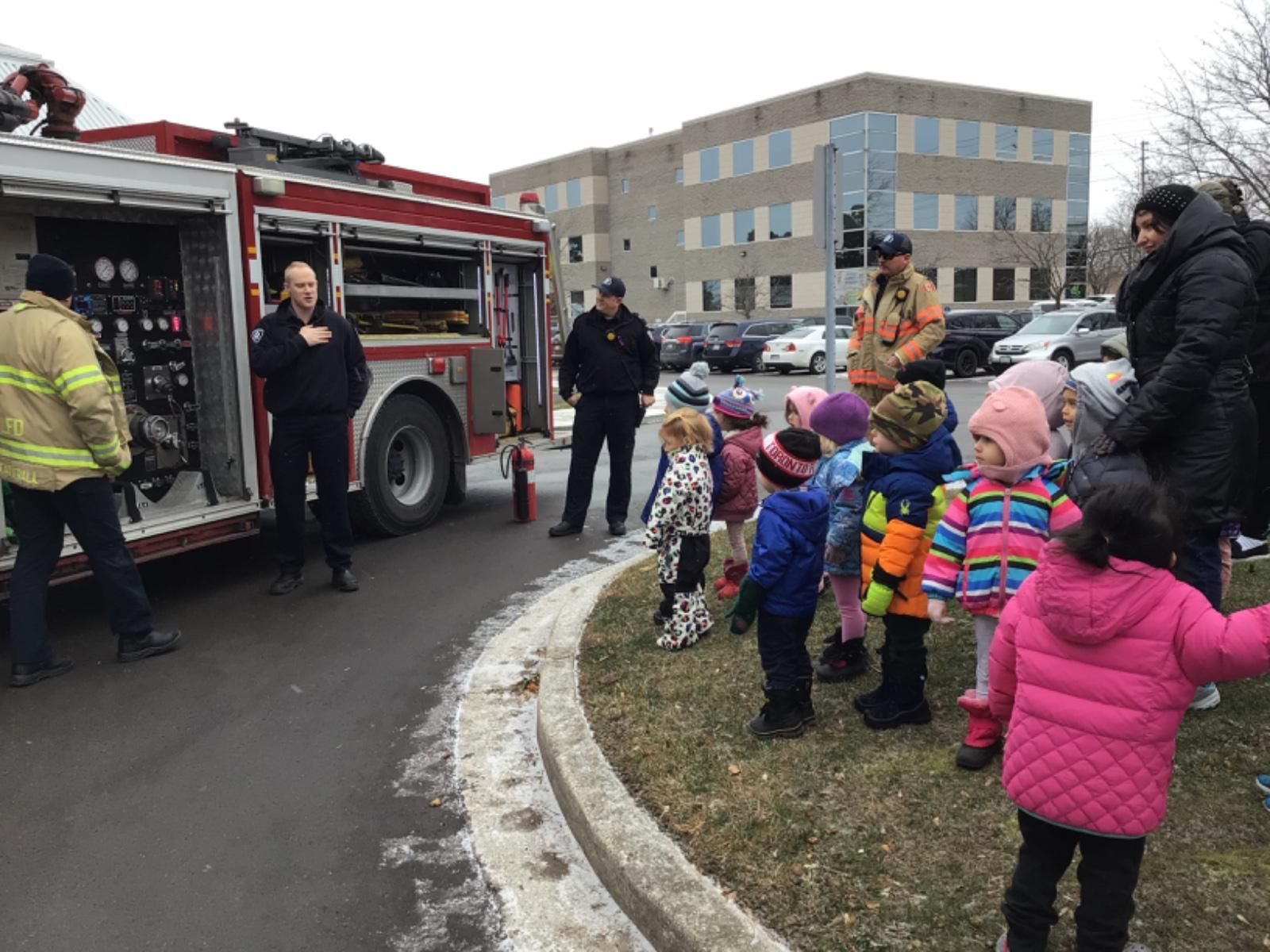 A group of children are standing in front of a fire truck.