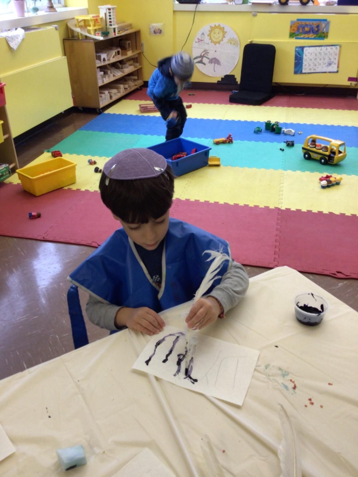 A young boy is sitting at a table writing on a piece of paper