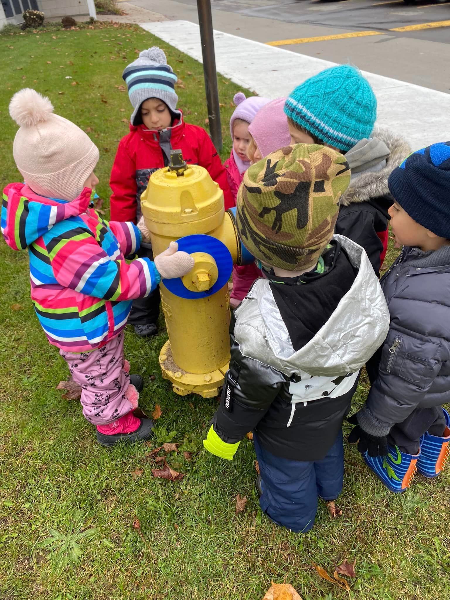 A group of children are standing around a fire hydrant.