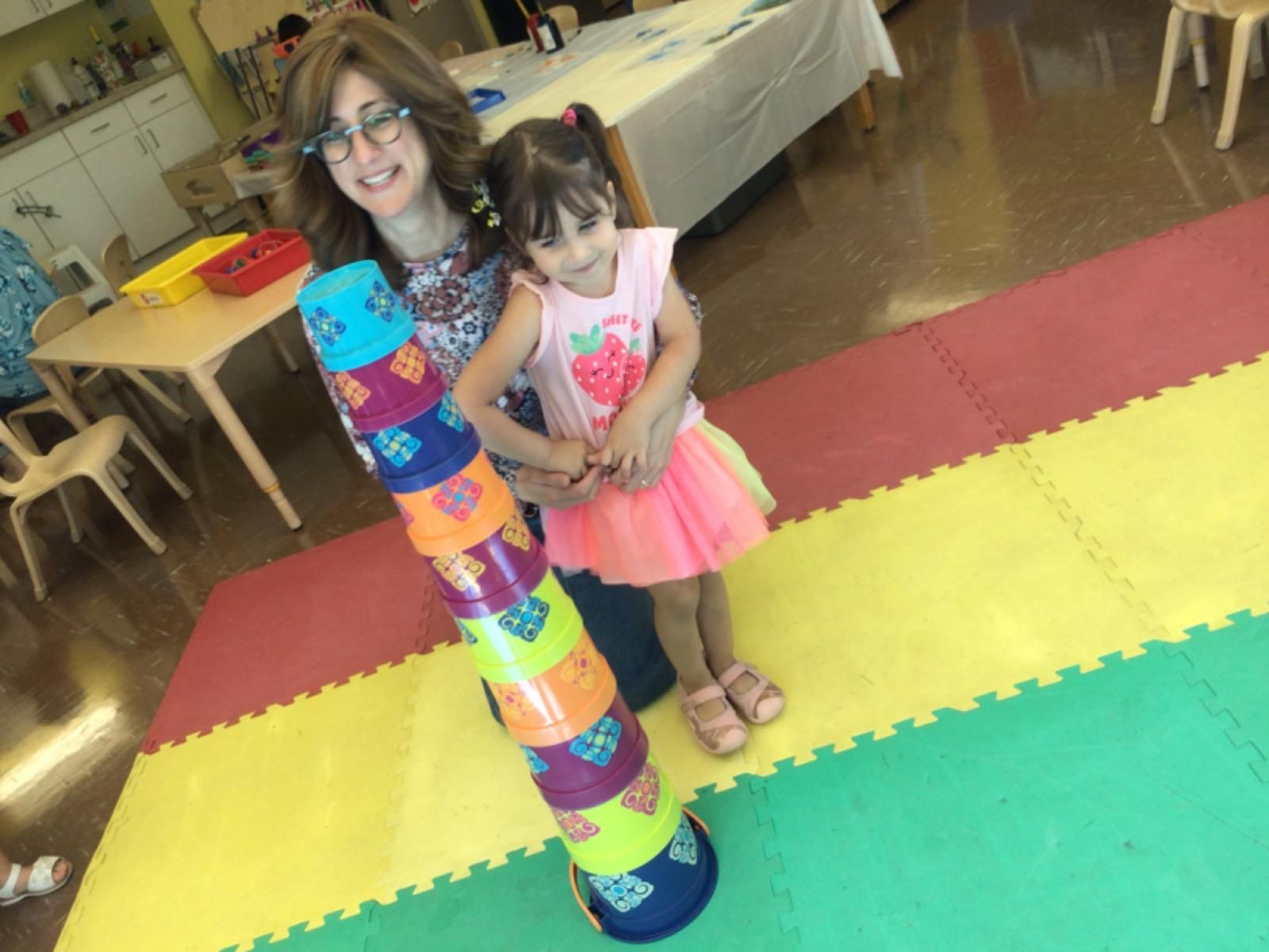 A woman and a little girl are standing next to a stack of plastic cups.
