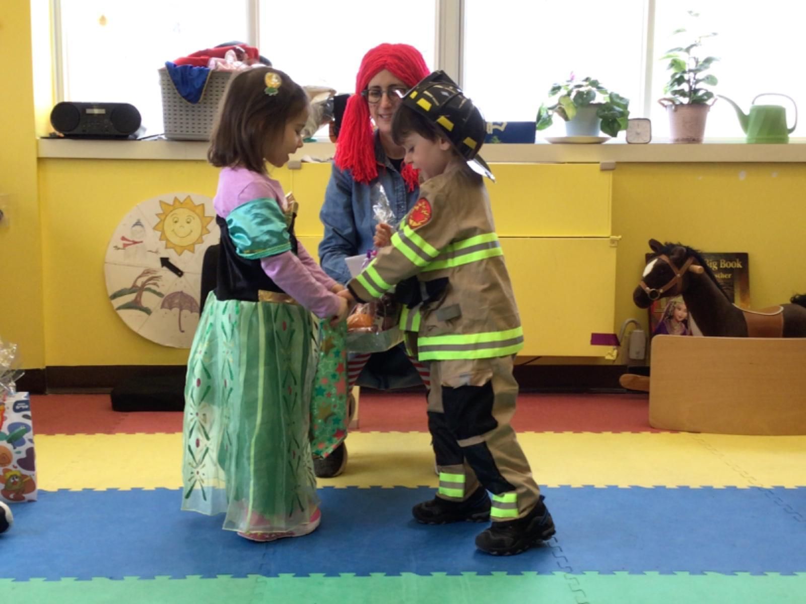 A little girl dressed as a princess and a little boy dressed as a fireman