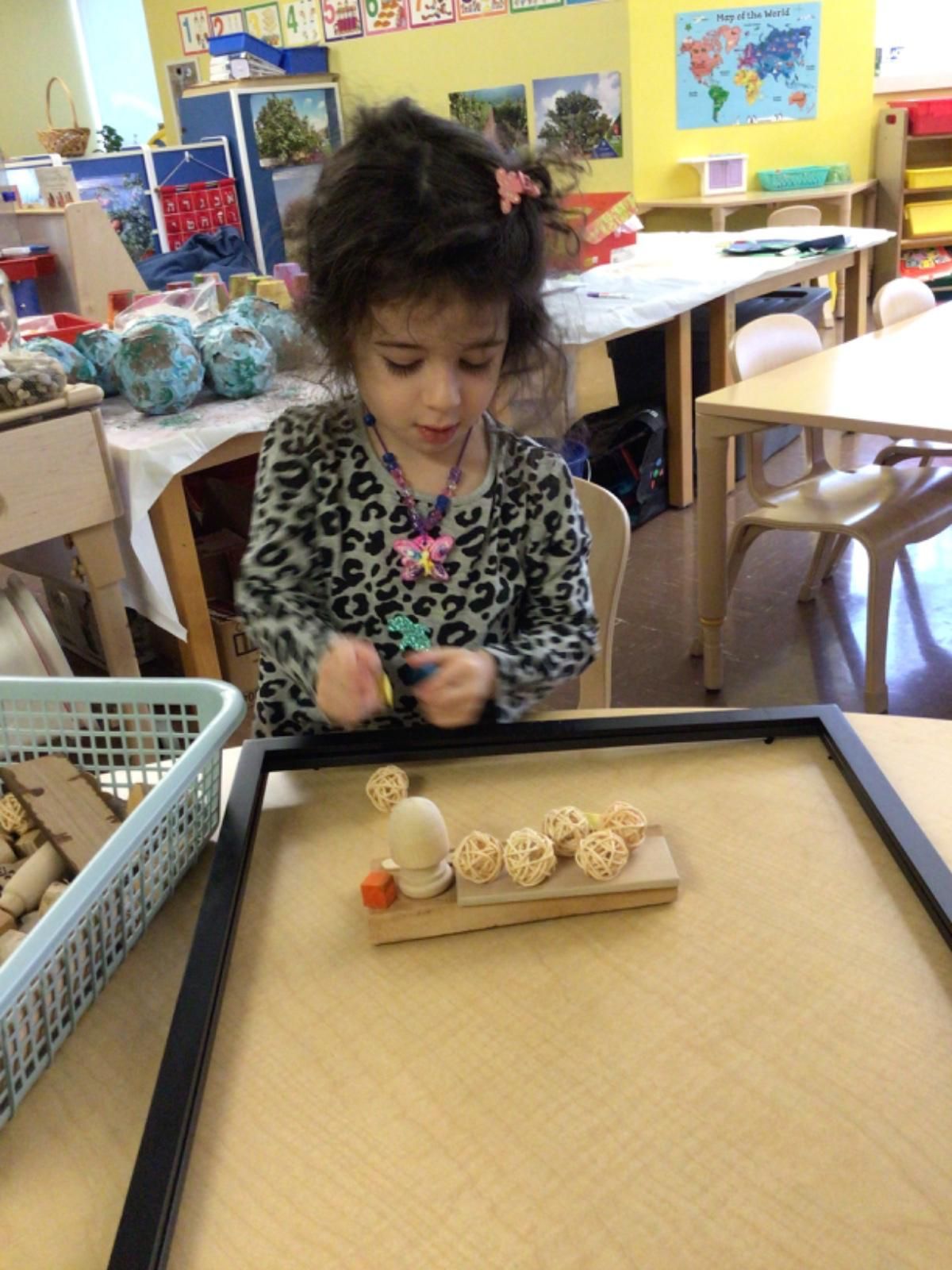 A little girl is playing with wooden toys in a classroom