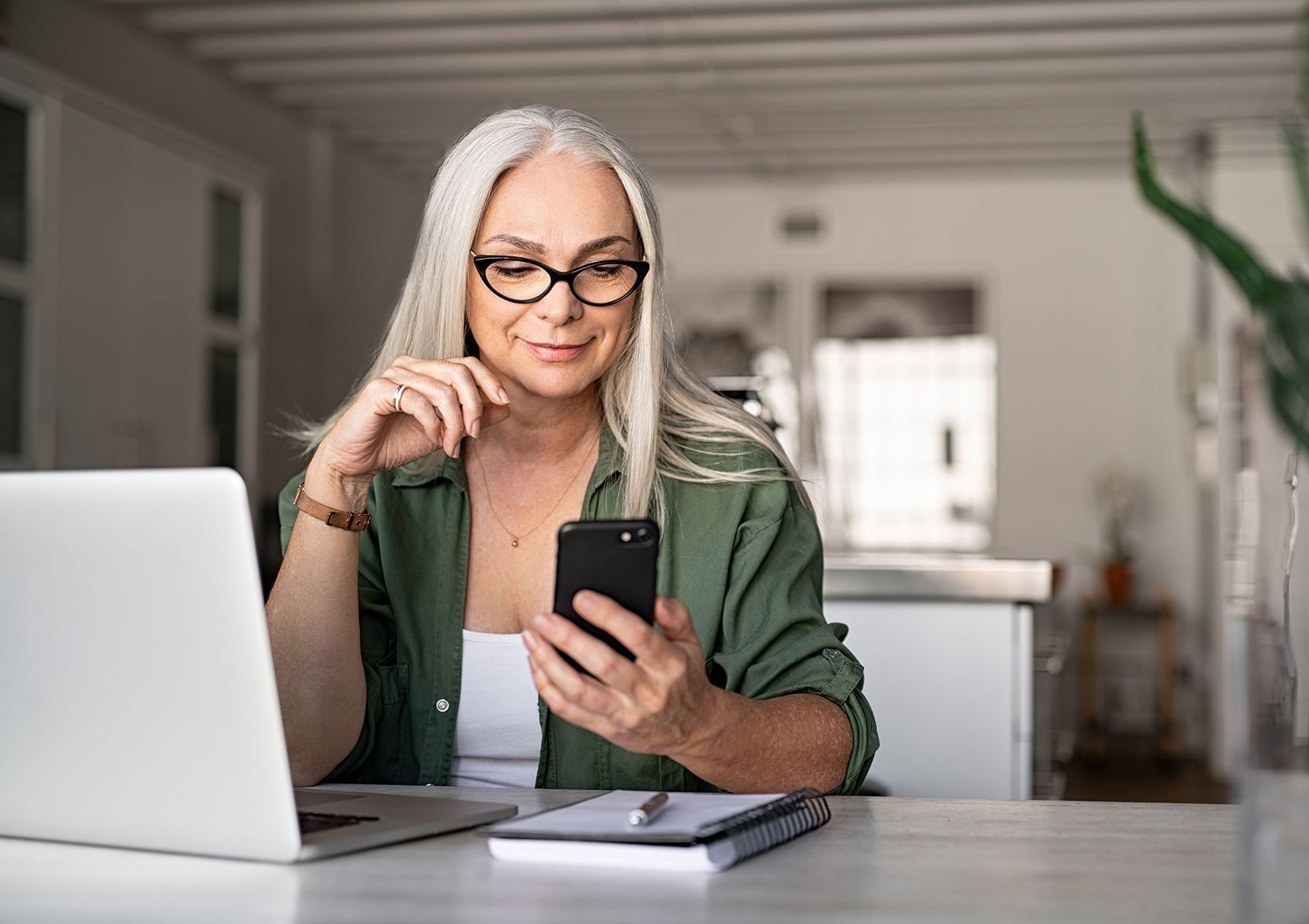 A man and a woman are sitting on a couch looking at a cell phone.
