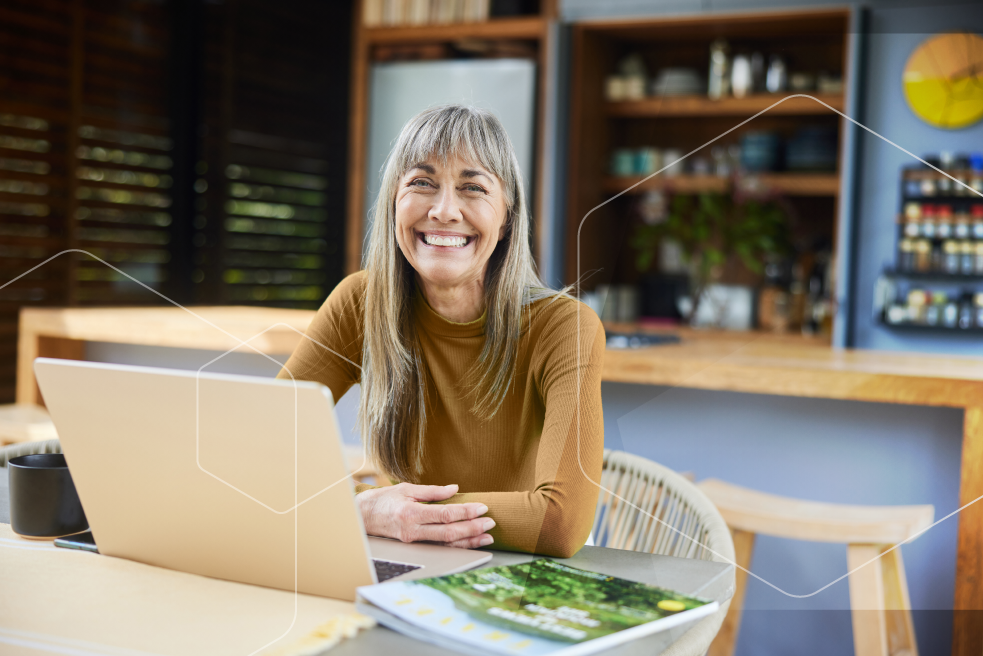A woman is sitting at a table with a laptop and a magazine.