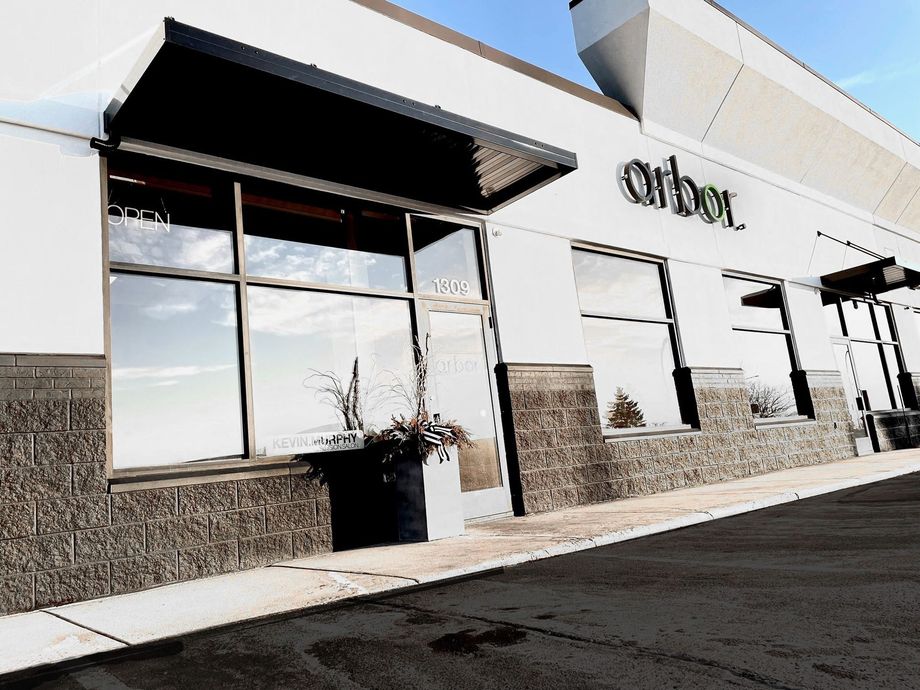 Brown mug and two haircare products next to a plant on a shelf.