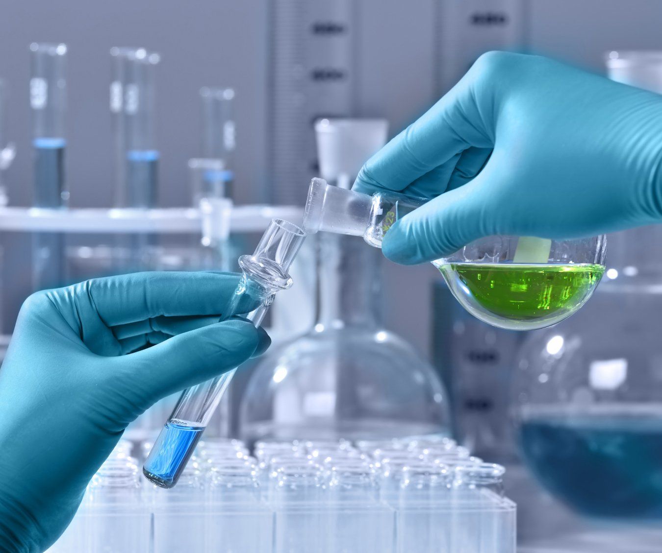 A scientist is pouring a green liquid into a beaker.