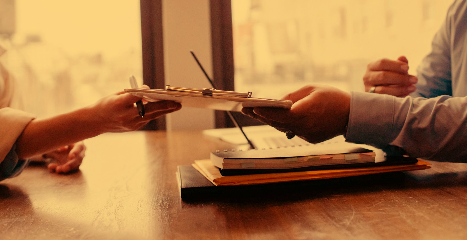 Hands exchanging money over a desk, likely a transaction.