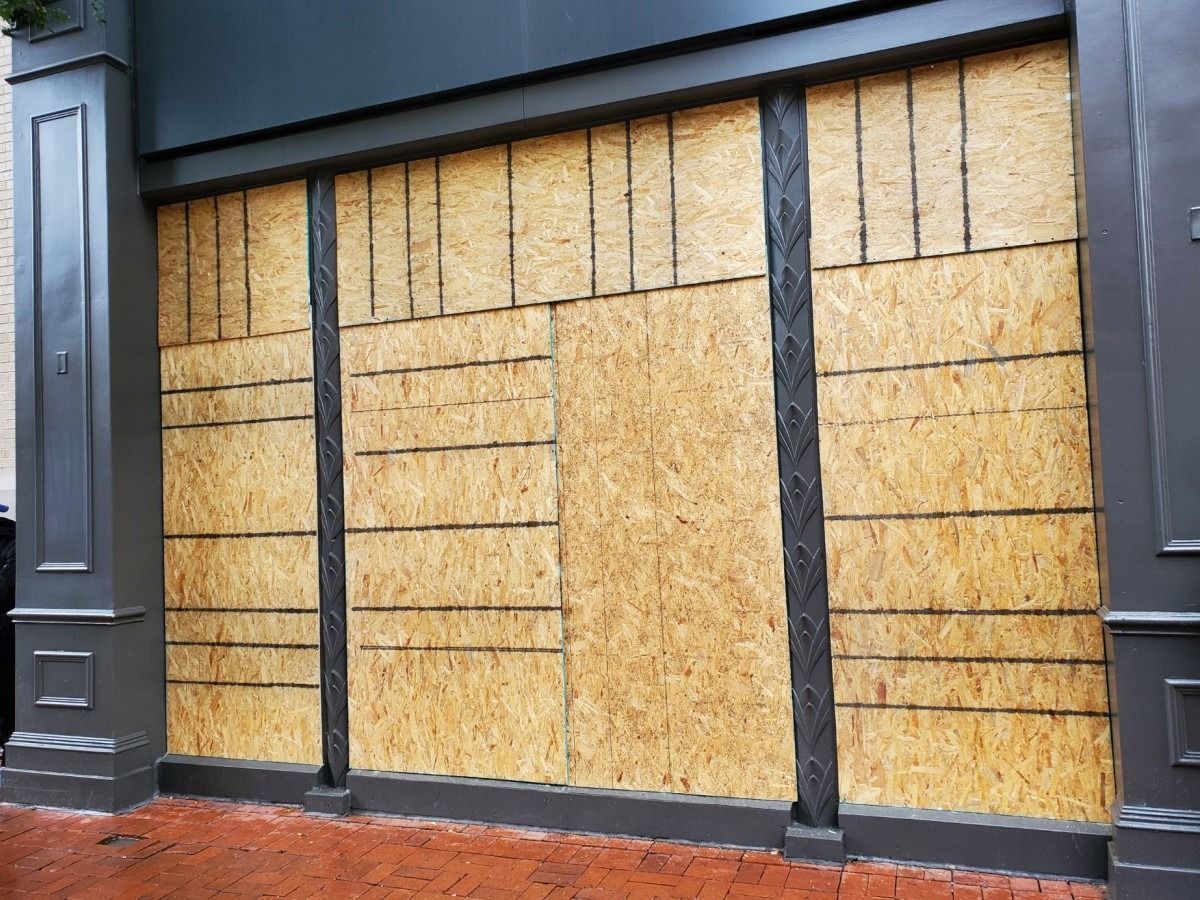 A building with a lot of windows covered in plywood.
