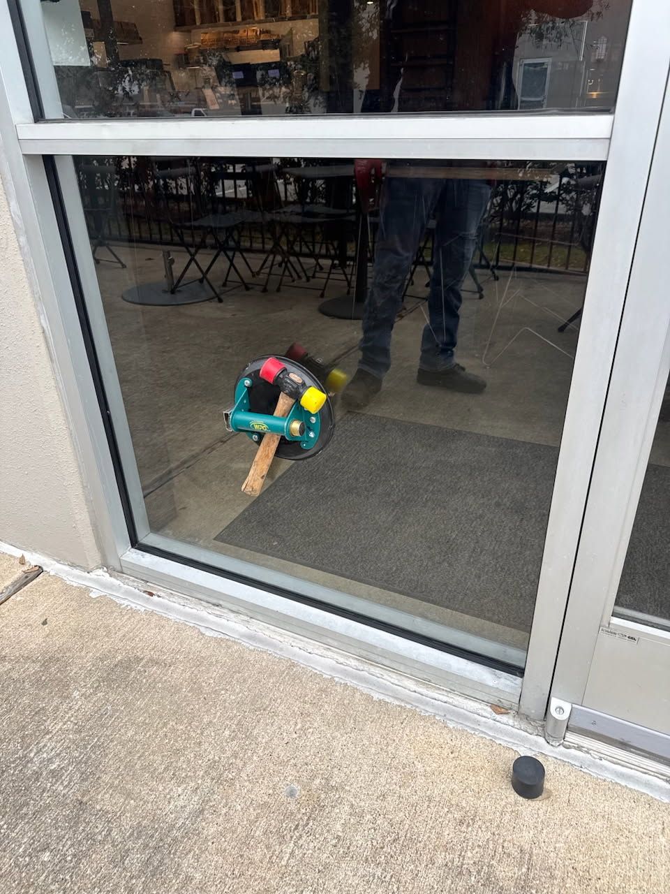 A toy hammer is sticking out of a glass door.