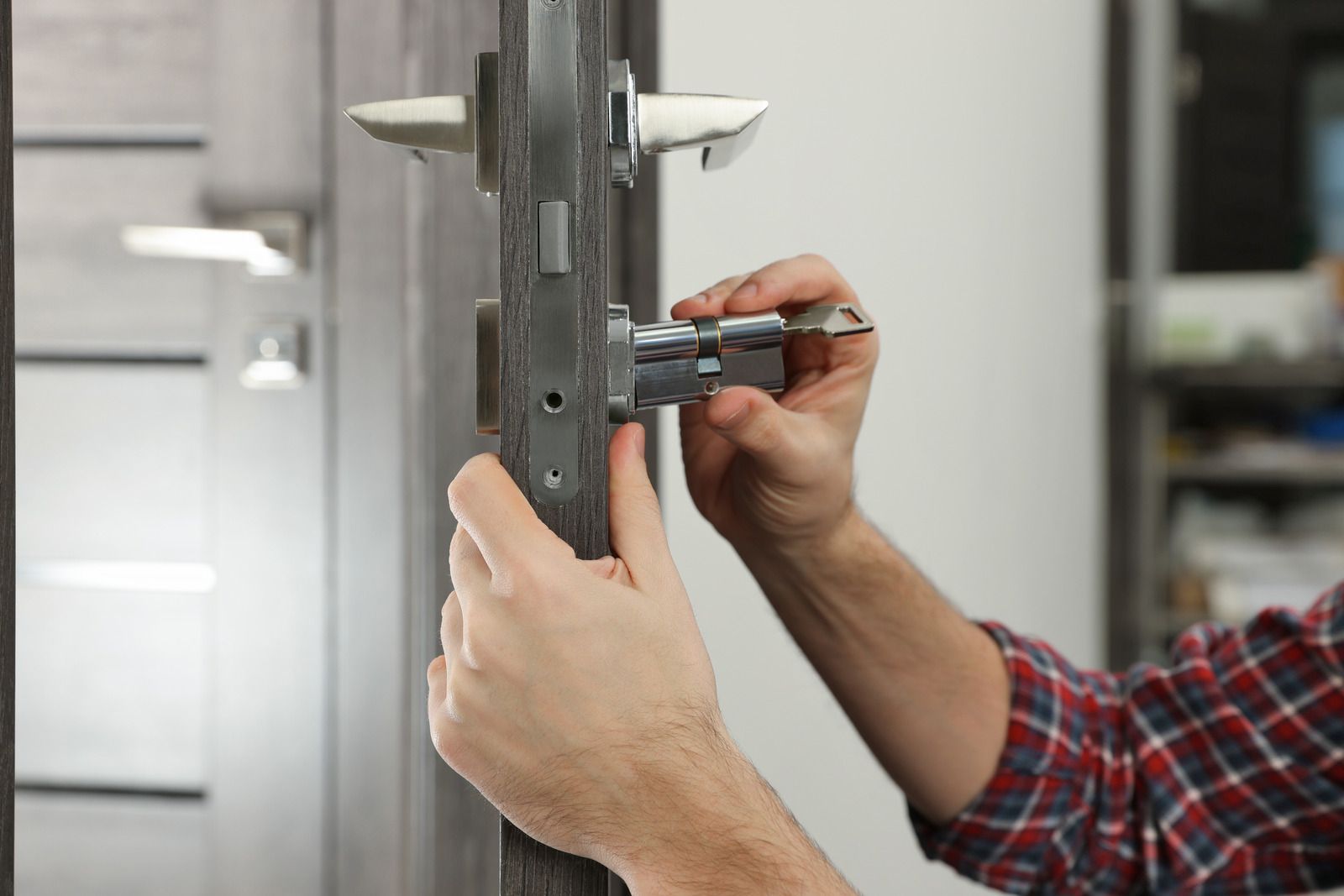 A man is fixing a door lock with a screwdriver.