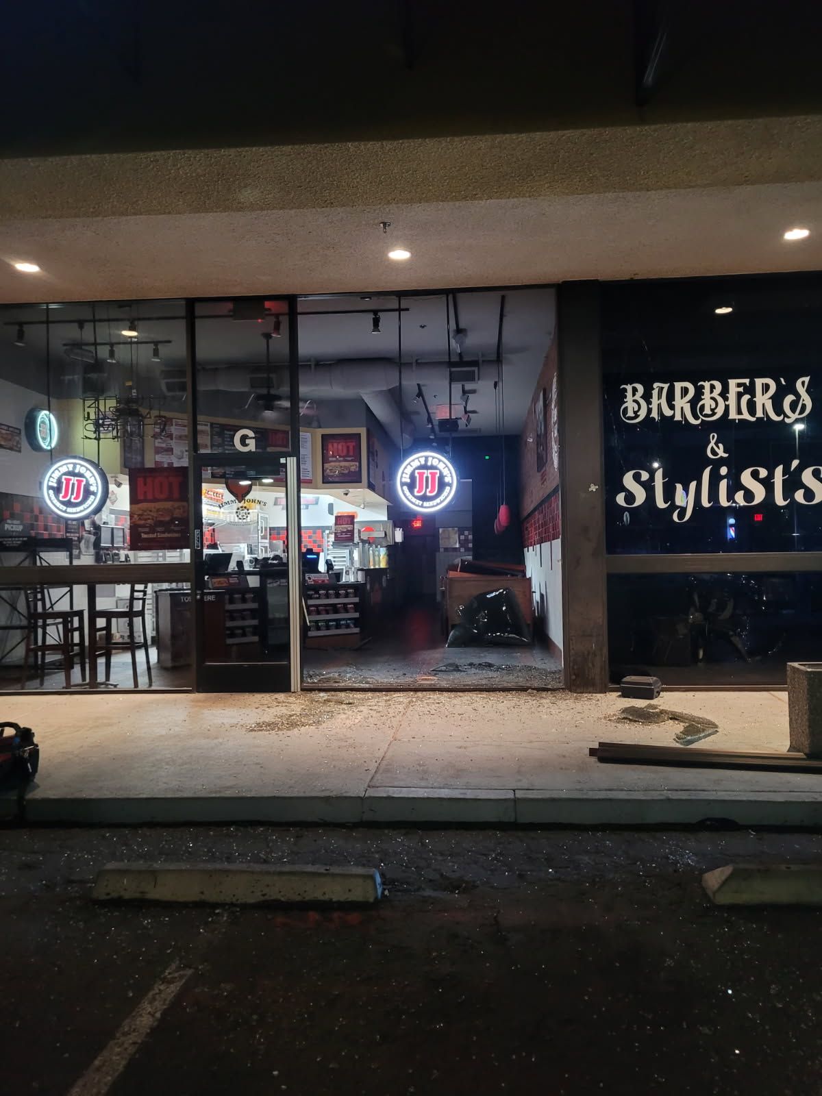 A barber shop with a broken window and a sign that says barbers and stylists