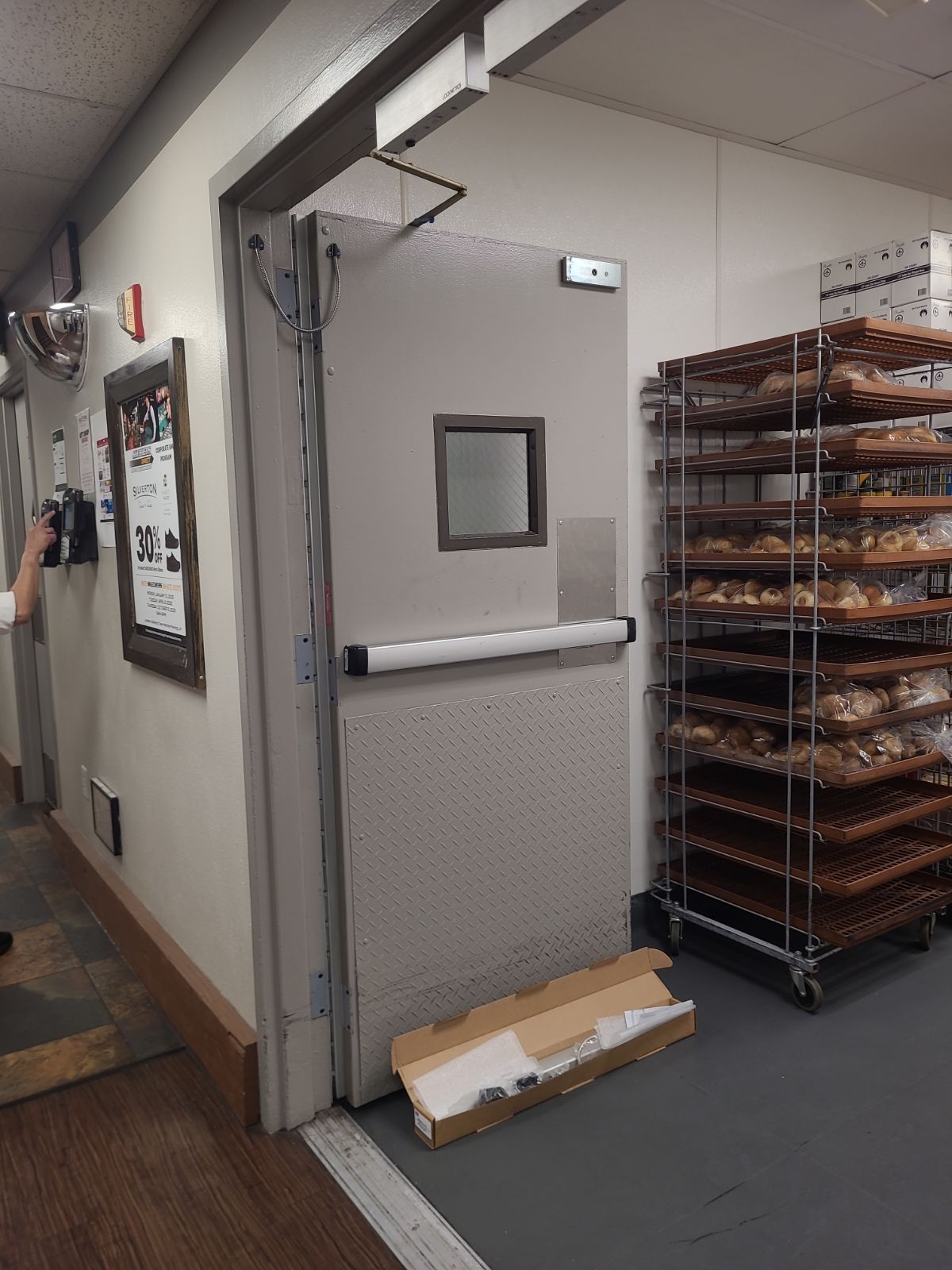 A bakery with a door that is open and a bunch of shelves of bread.
