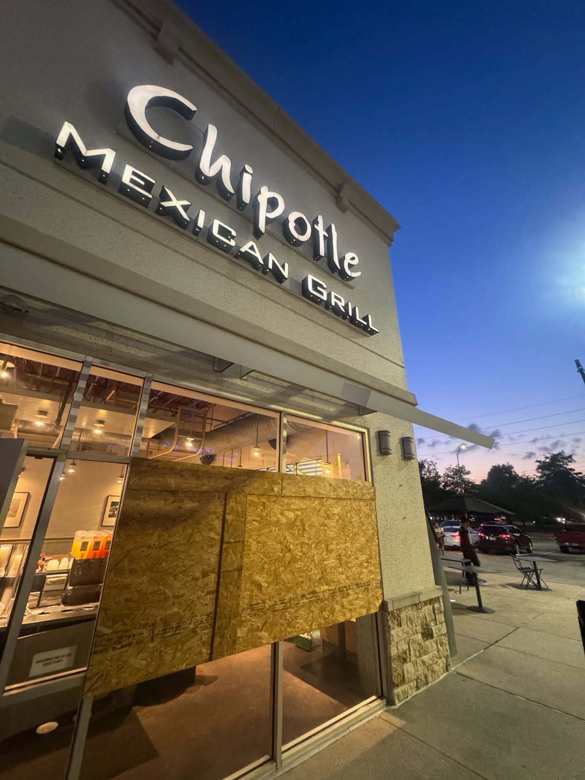A chipotle mexican grill is closed and covered in plywood.
