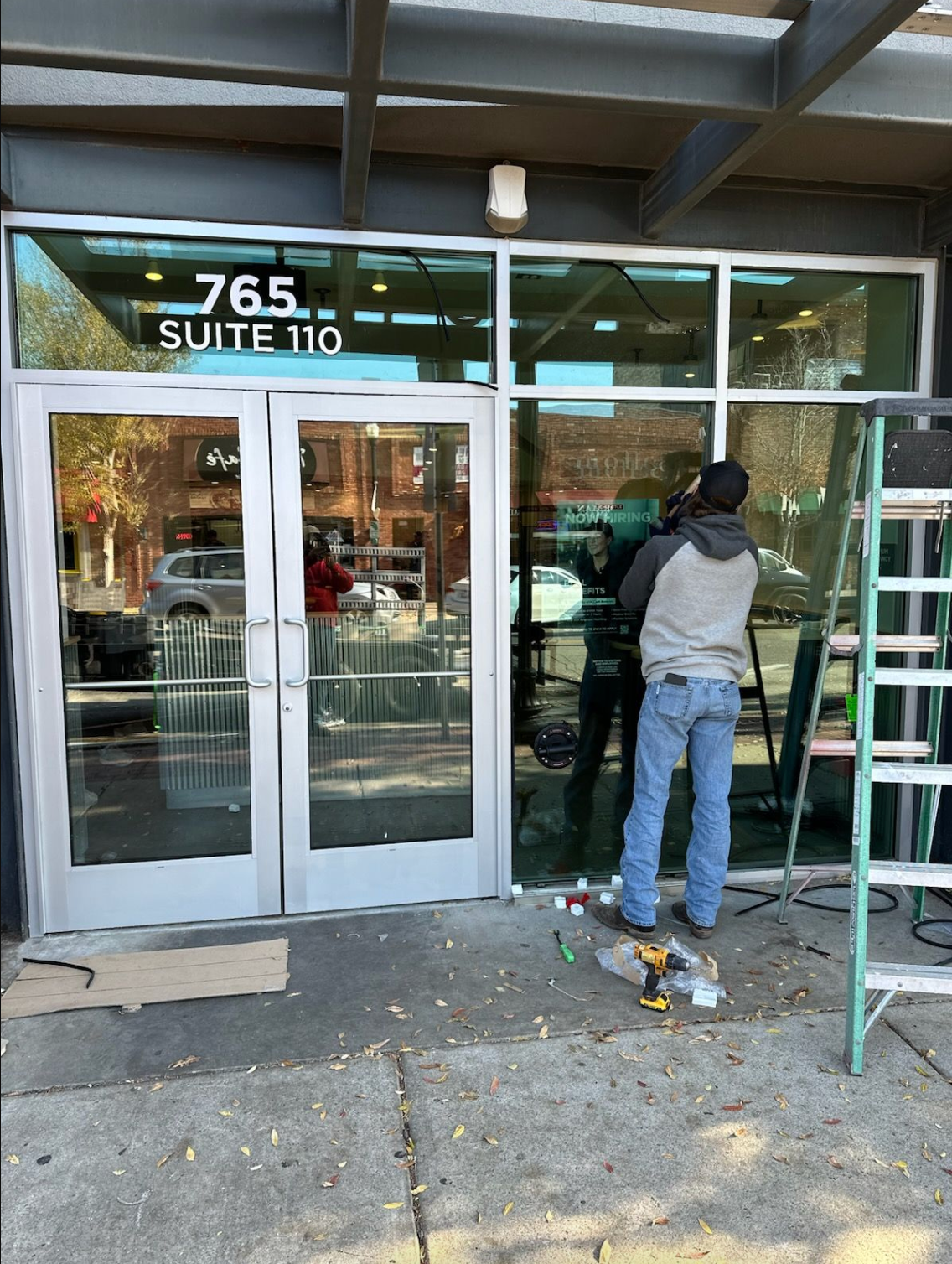 A man is installing a glass door in front of a building.