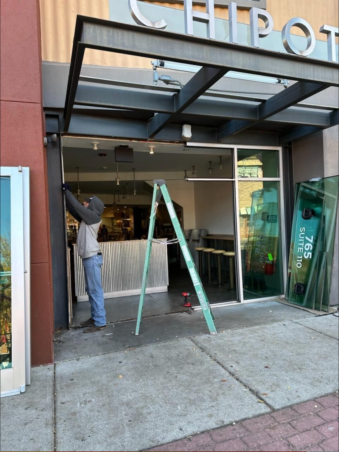 A man standing on a ladder in front of a chipotle restaurant